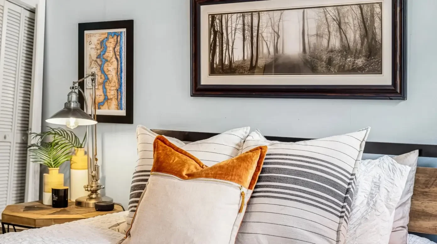 Bedroom styling featuring rust orange velvet pillows and framed St. Johns River map art for local character.