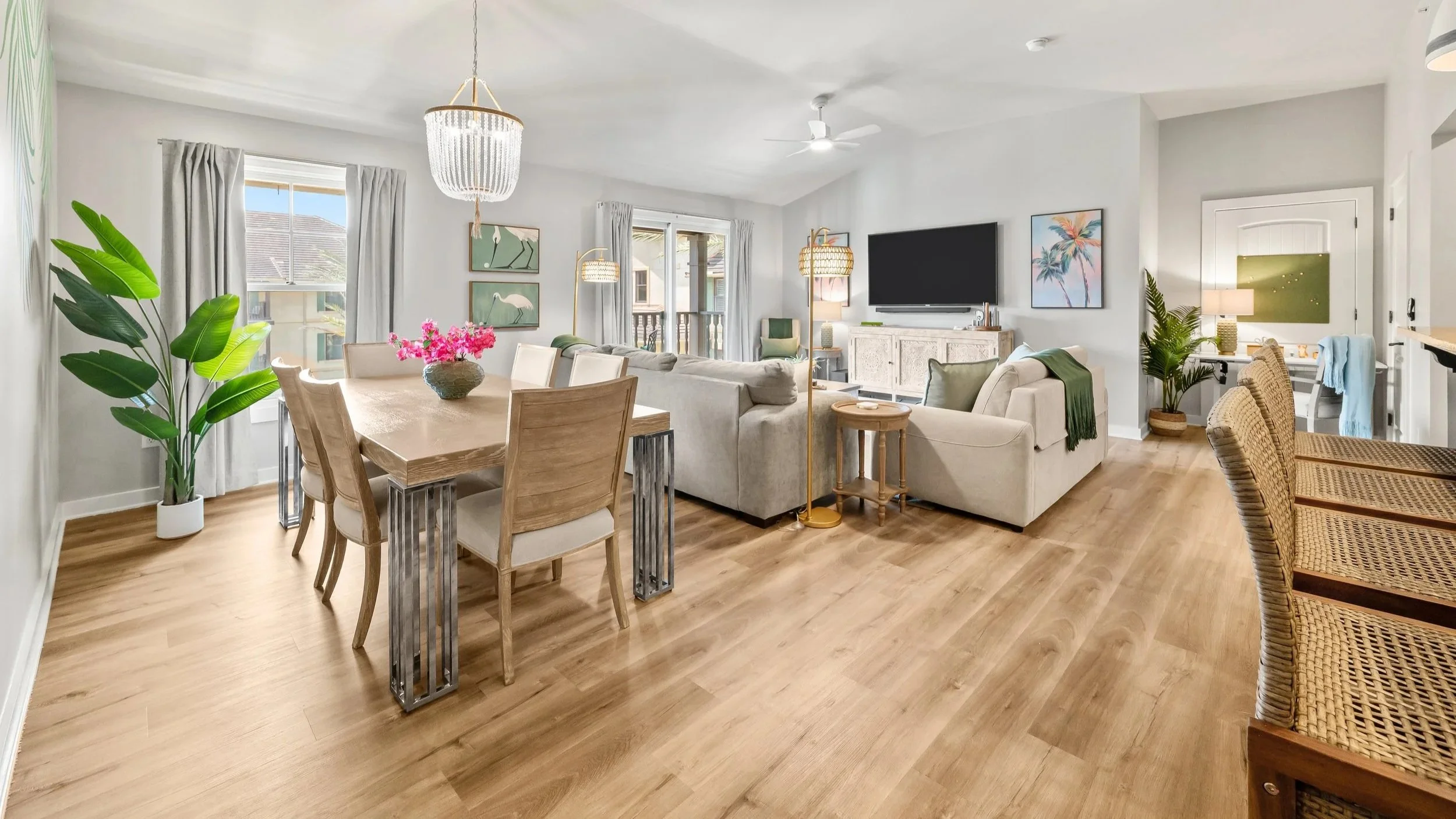 Open living room and dining space with neutral furnishings, warm wood floors, and layered lighting designed for comfort and easy gathering.