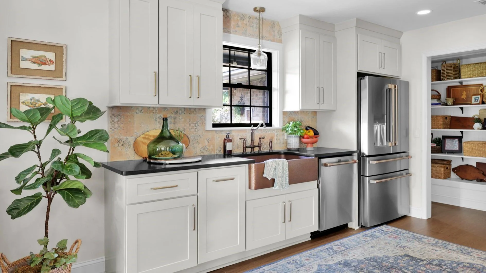 White shaker kitchen with black countertops, copper apron-front sink, patterned tile backsplash, and stainless fridge
