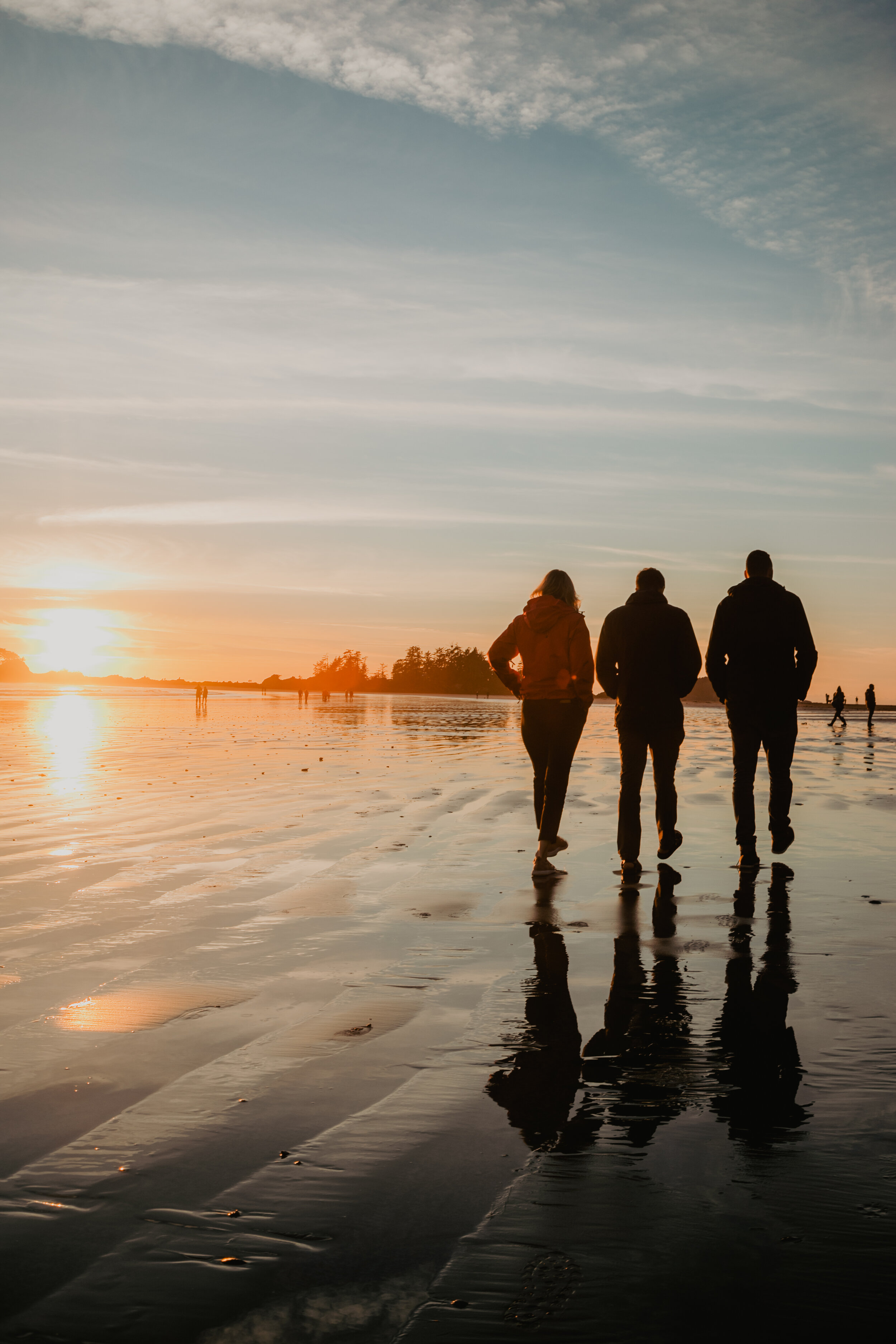 People walking along the beach at sunset in Tofino
