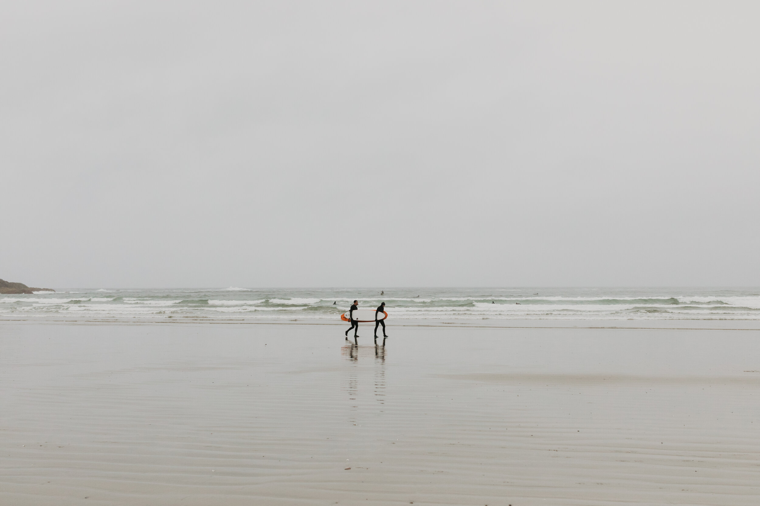 People carrying a surfboard in the rain at Long Beach