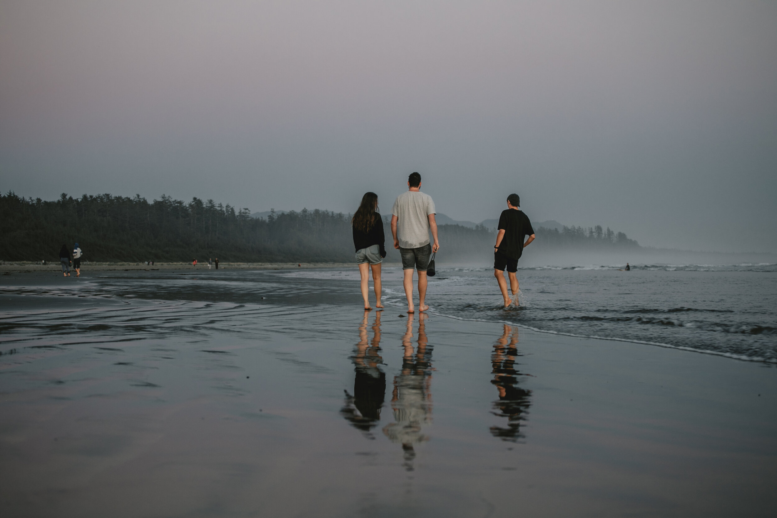 Group of friends walking along the beach in Tofino