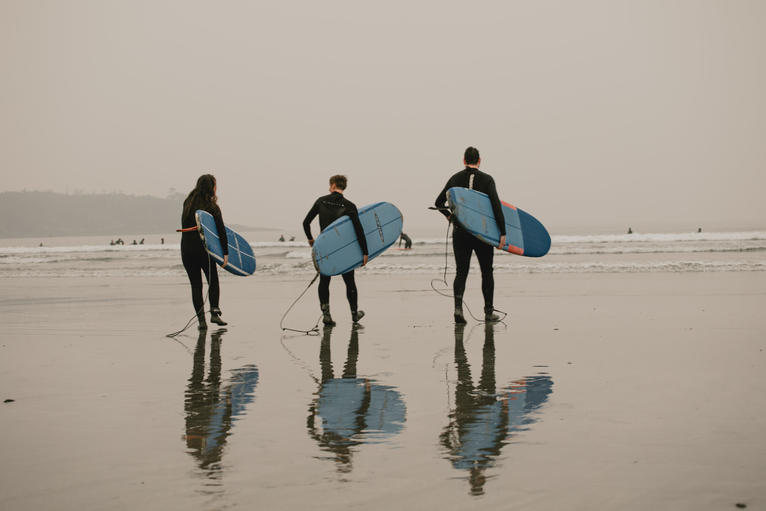Group of friends walking towards the waves during a Long Beach Lodge surfing lesson