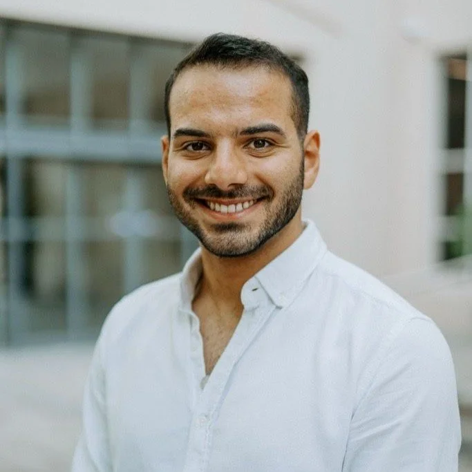 Smiling man in white shirt with trimmed facial hair.