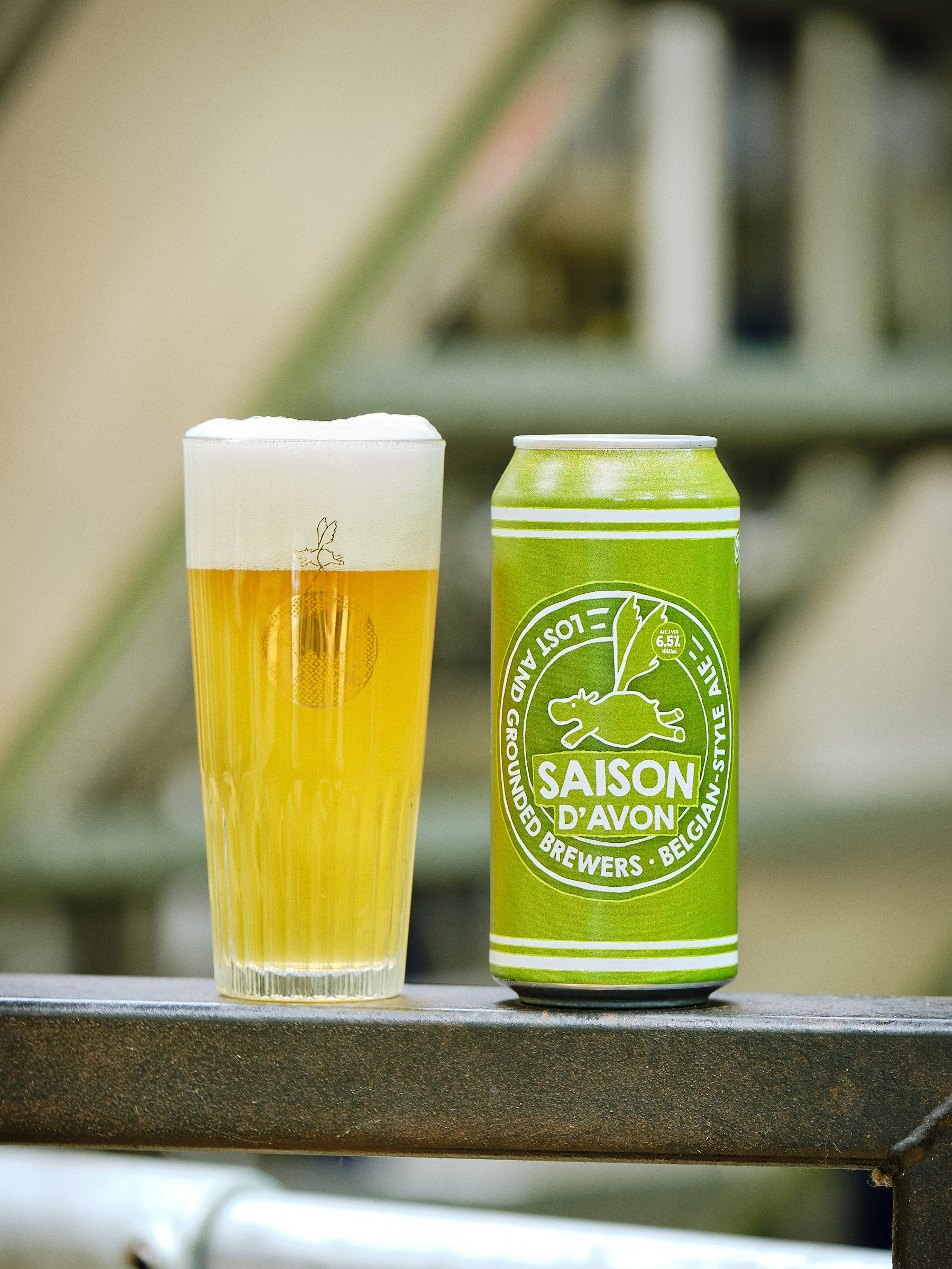 A can of Lost and Grounded 'Saison D'Avon' (Belgian-style Ale 6.5%), next to a filled glass with the brewery in the background.