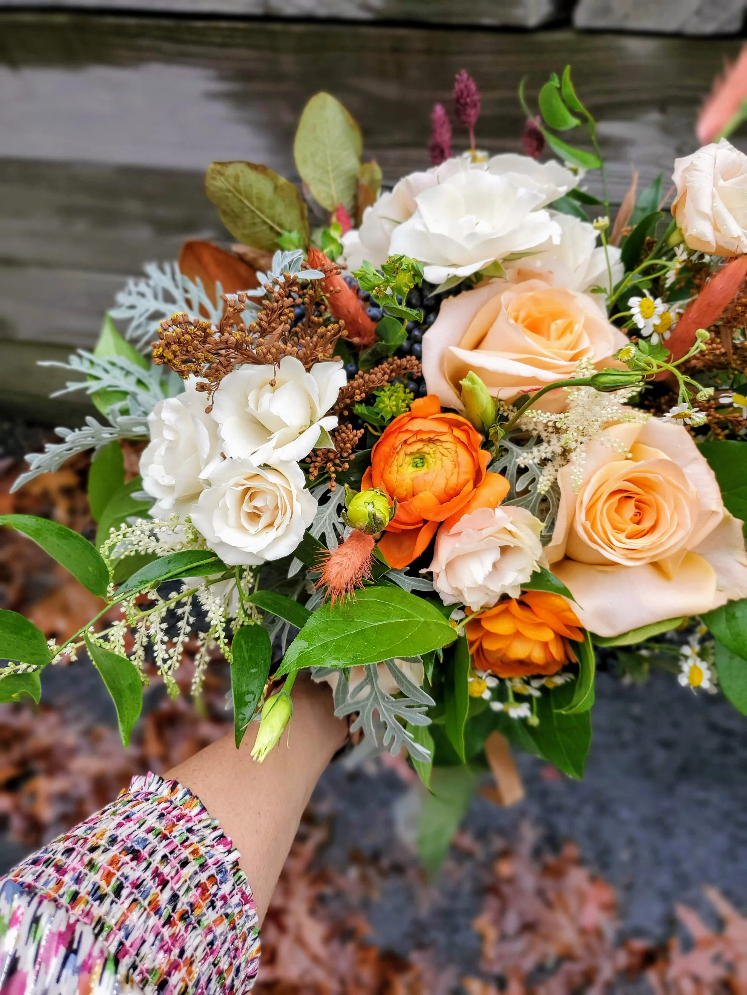 Fairytale fall wedding with ranunculus, dusty miller, privet berry, fancy spray roses, and delicate ribbon.