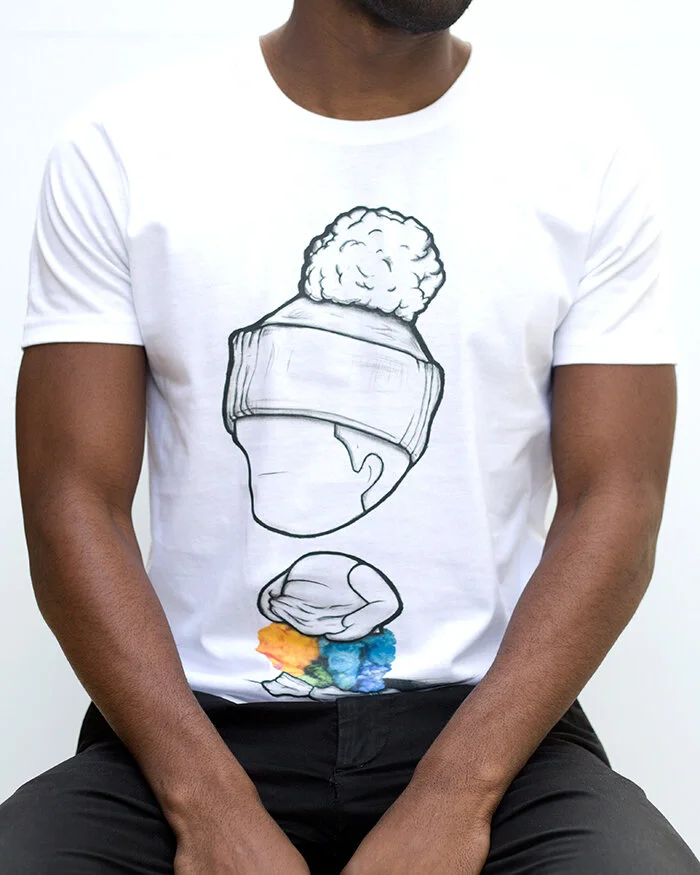 A man wearing a white T-shirt with a line drawing of a person wearing virtual reality goggles and a head full of curly hair. The drawing includes colorful splashes at the base.