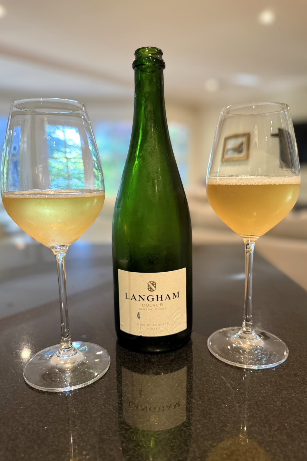 Bottle of Langham sparkling wine with two wine glasses filled with golden sparkling wine