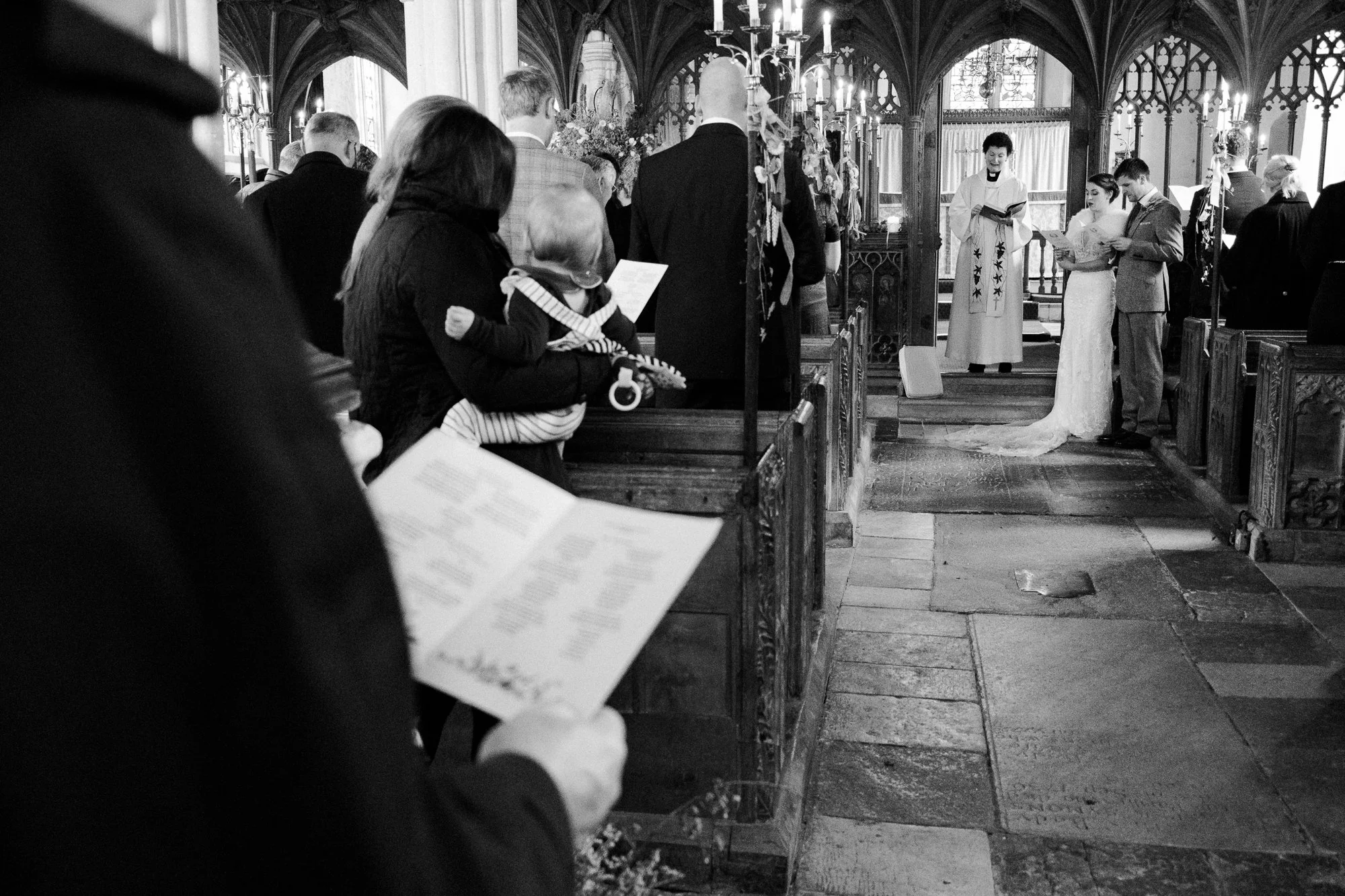 Bride and Groom and guests sing during their wedding ceremony Saint John the Baptist Church at The Great Barn, Exeter, Devon.