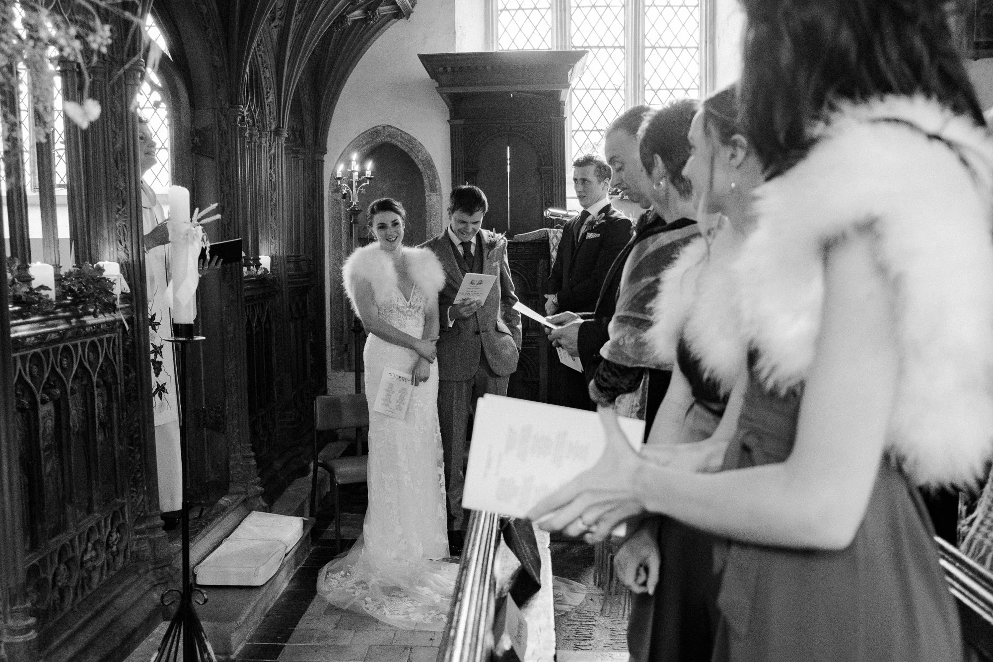 Bride and Groom and guests during their wedding ceremony Saint John the Baptist Church at The Great Barn, Exeter, Devon.