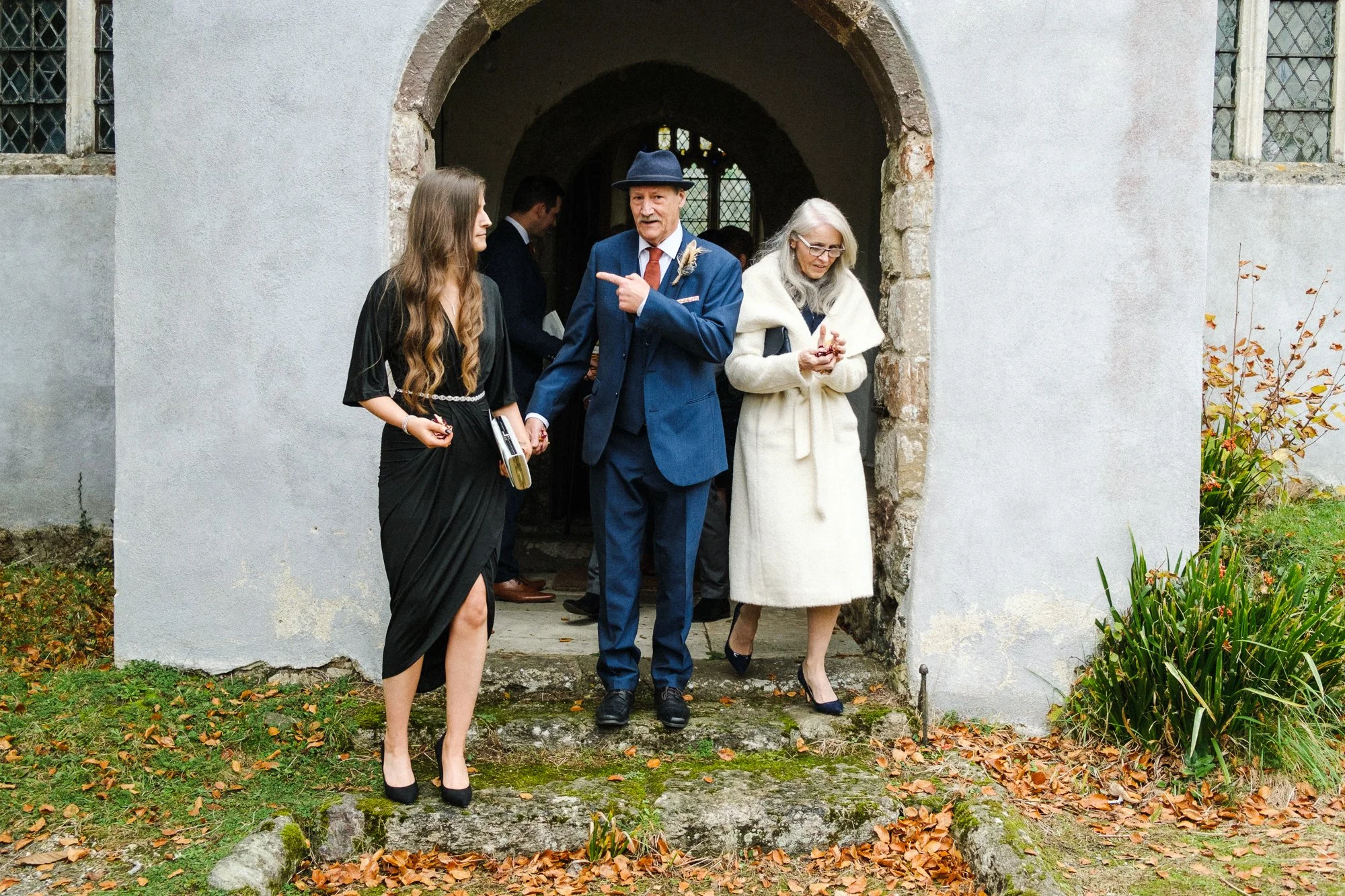 Wedding guests leaving the ceremony Saint John the Baptist Church at The Great Barn, Exeter, Devon.