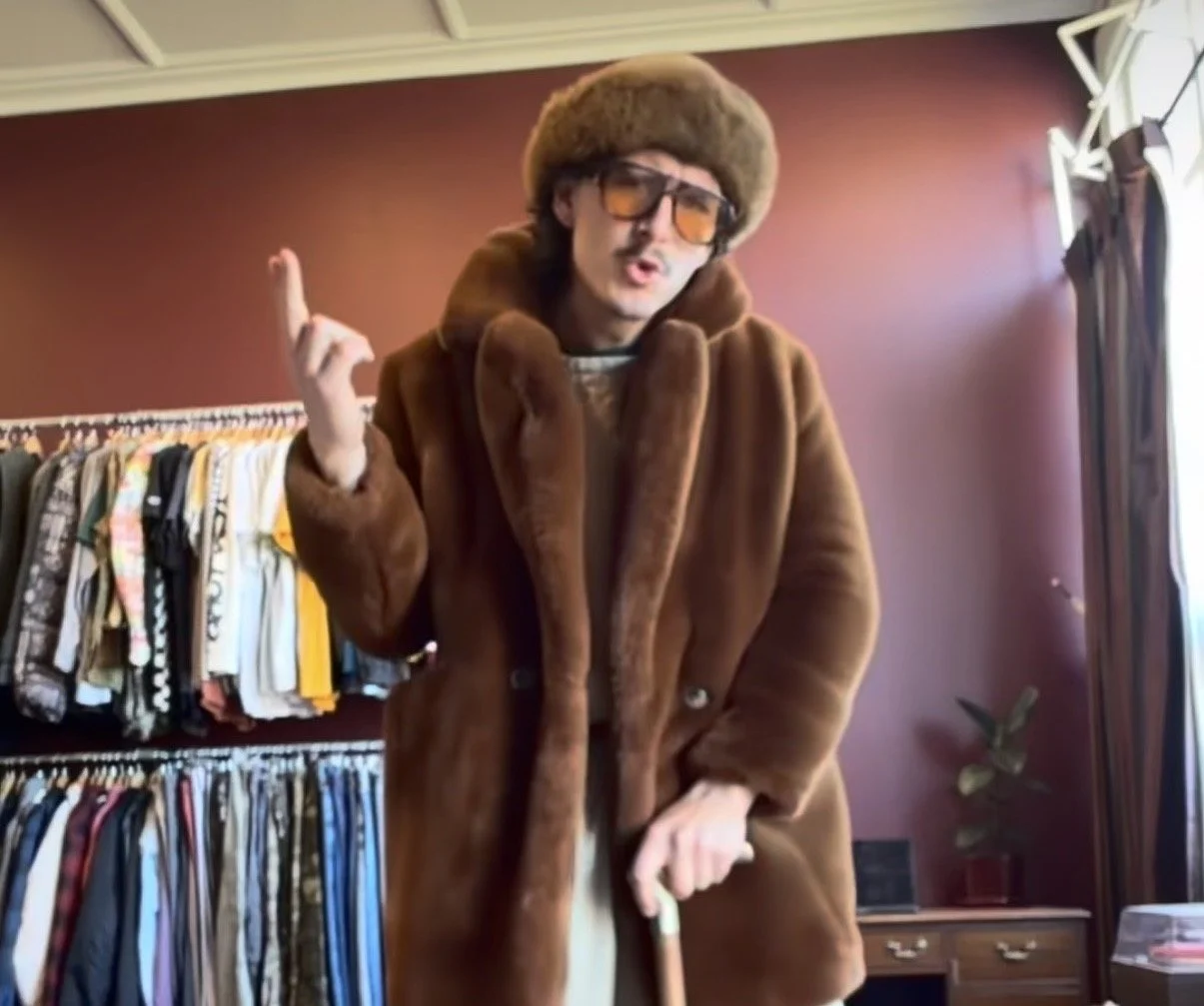 Man wearing a pre-loved fur coat inside a shop