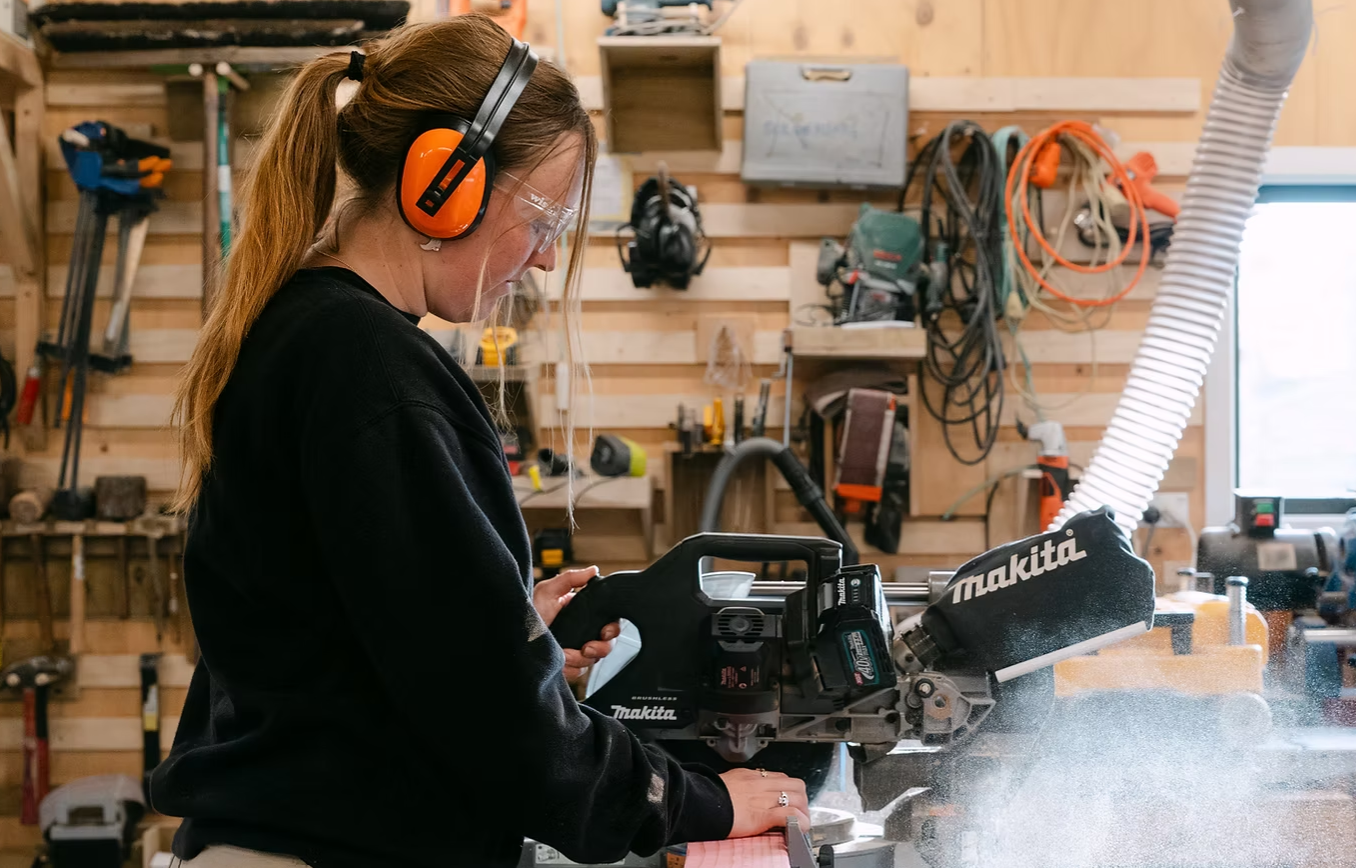 A women using a drop saw inside the Women shed in Queenstown