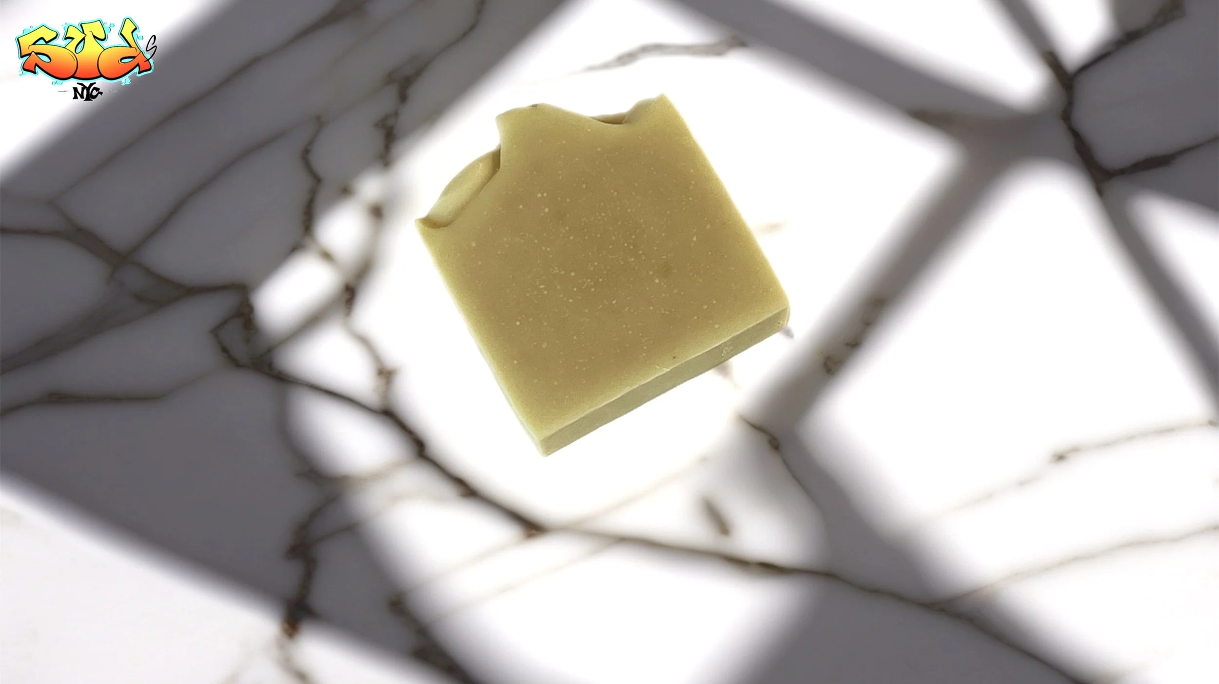 Angled view of Golden Equinox handmade carrot powder soap resting on white marble, highlighting its golden color, smooth sides, and artisan-crafted shape.