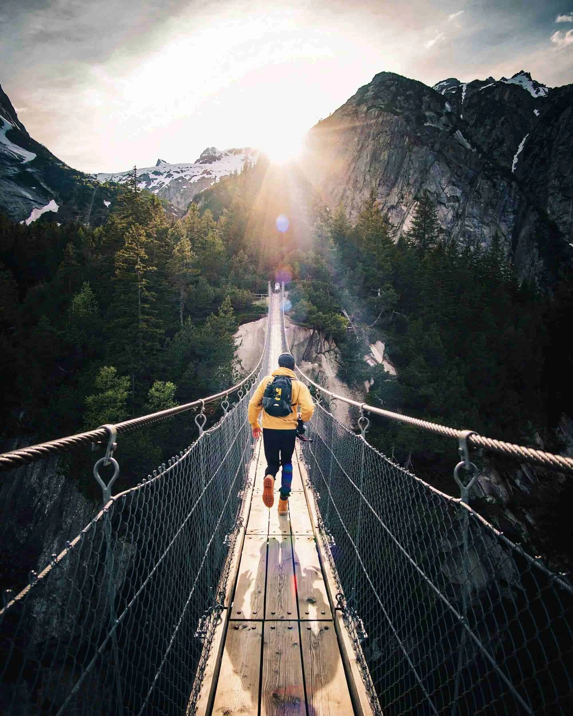hiker racing across a metal wire bridge in the mountains