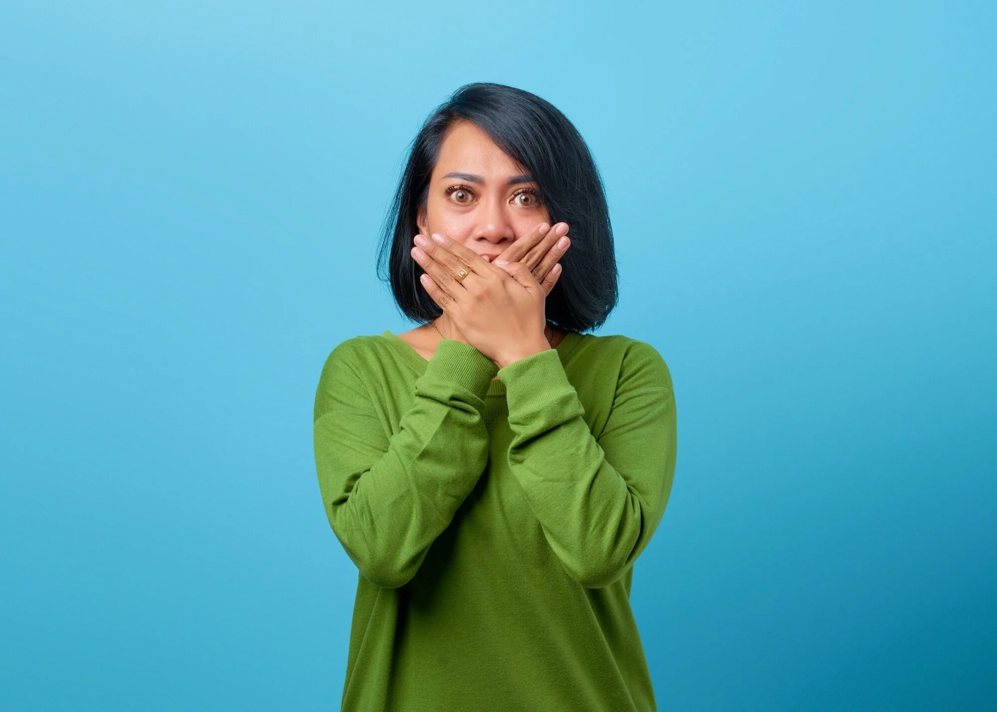 A woman with hands over mouth signaling a mistake