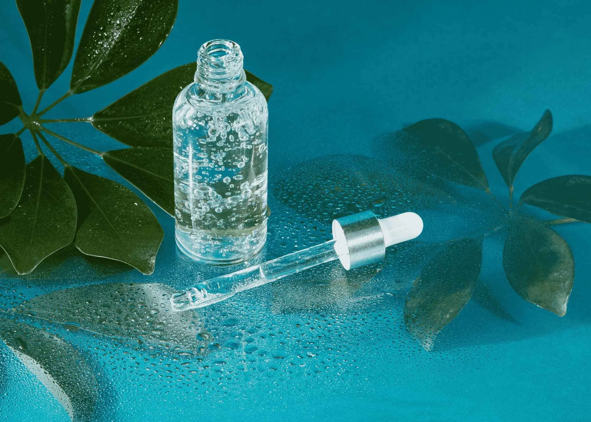 Picture of a glass vial of serum on a blue background with a plant accent
