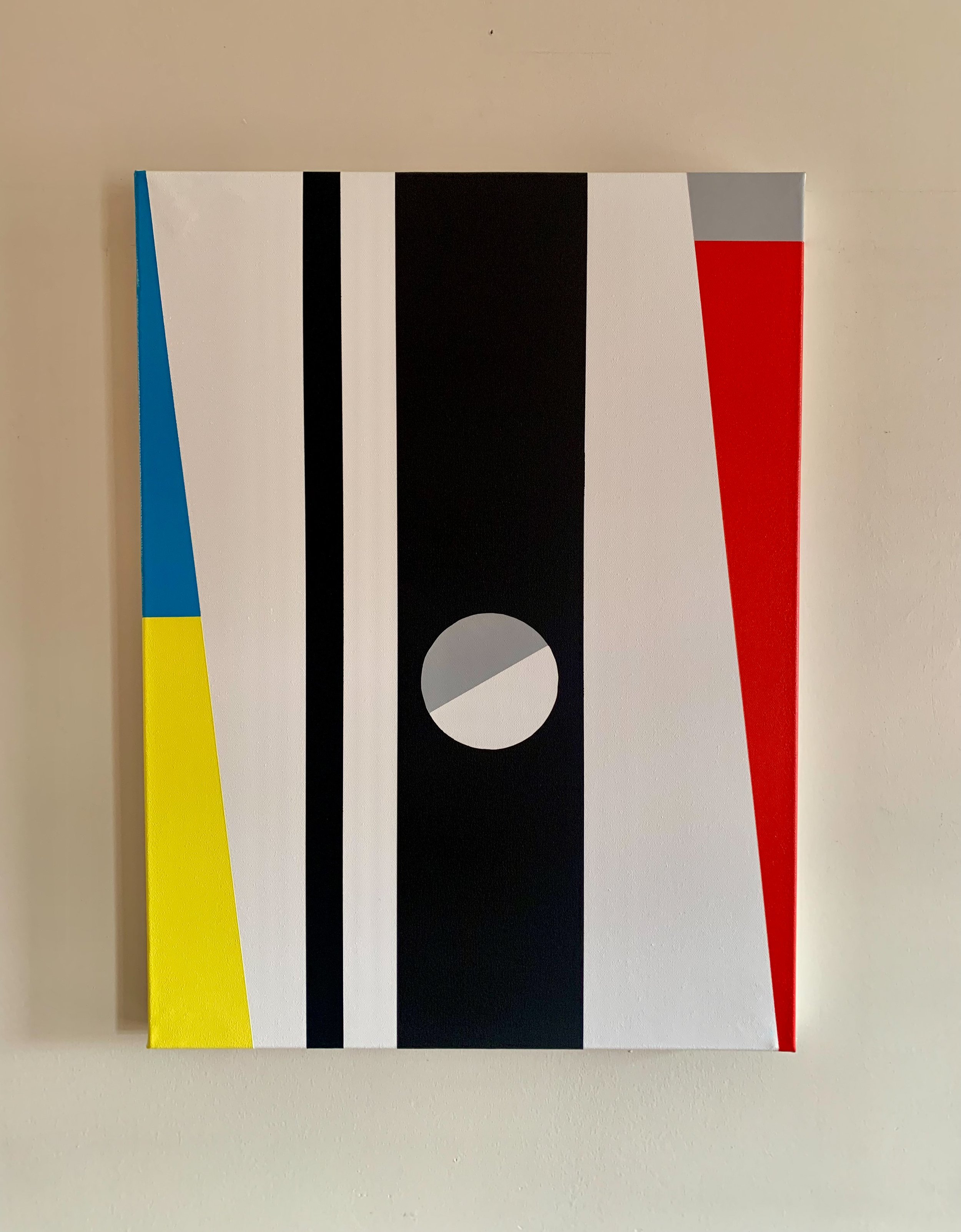 A modern interior with geometric abstract wall art, a black console table with books and vases, and a textured armchair.