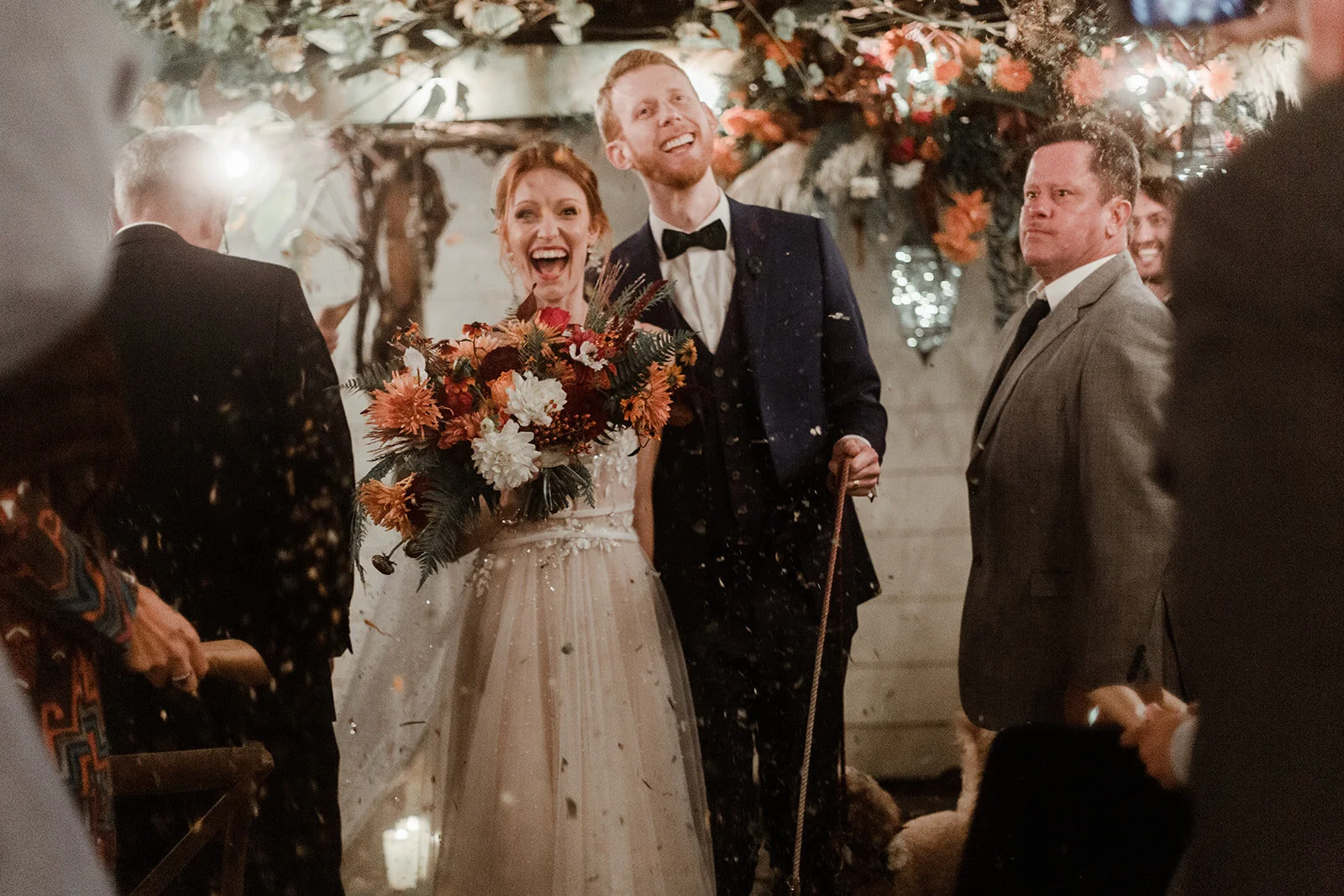 A happy smiling couple with a lush bridal bouquet in their backyard wedding.