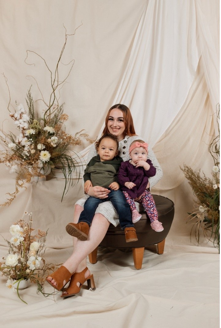 Sculptural floral arrangements framing mother and two children in a sweet family portrait. 