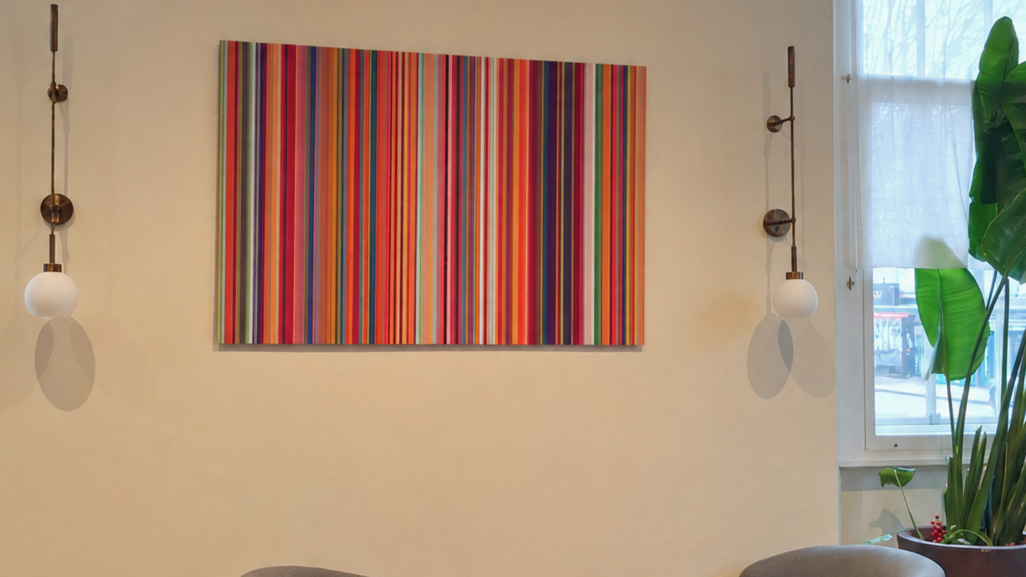 Prelude in E flat minor by Elizabeth Mikellides: a large ChromaLuxe work of vertical stripes in reds, oranges, purples and blues, hanging between brass wall lights in the cocktail bar of the Town Hall Hotel, London.