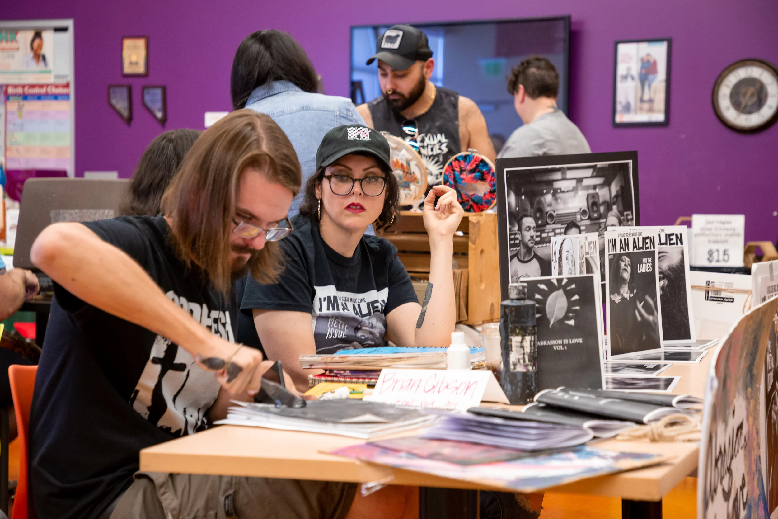 A vendor concentrates on a project while a colleague looks on.