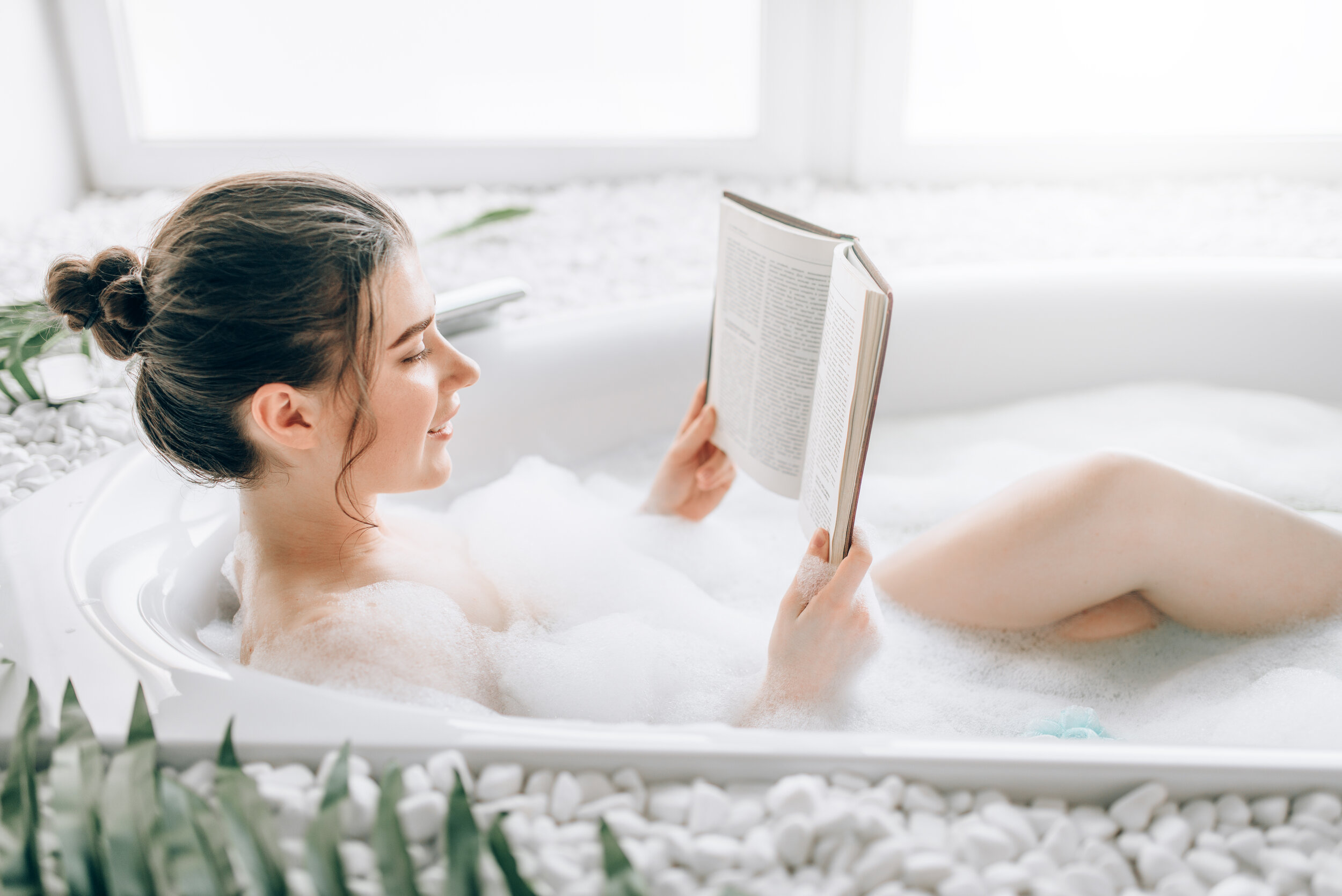 Woman lying in bath with foam and reads magazine.jpeg