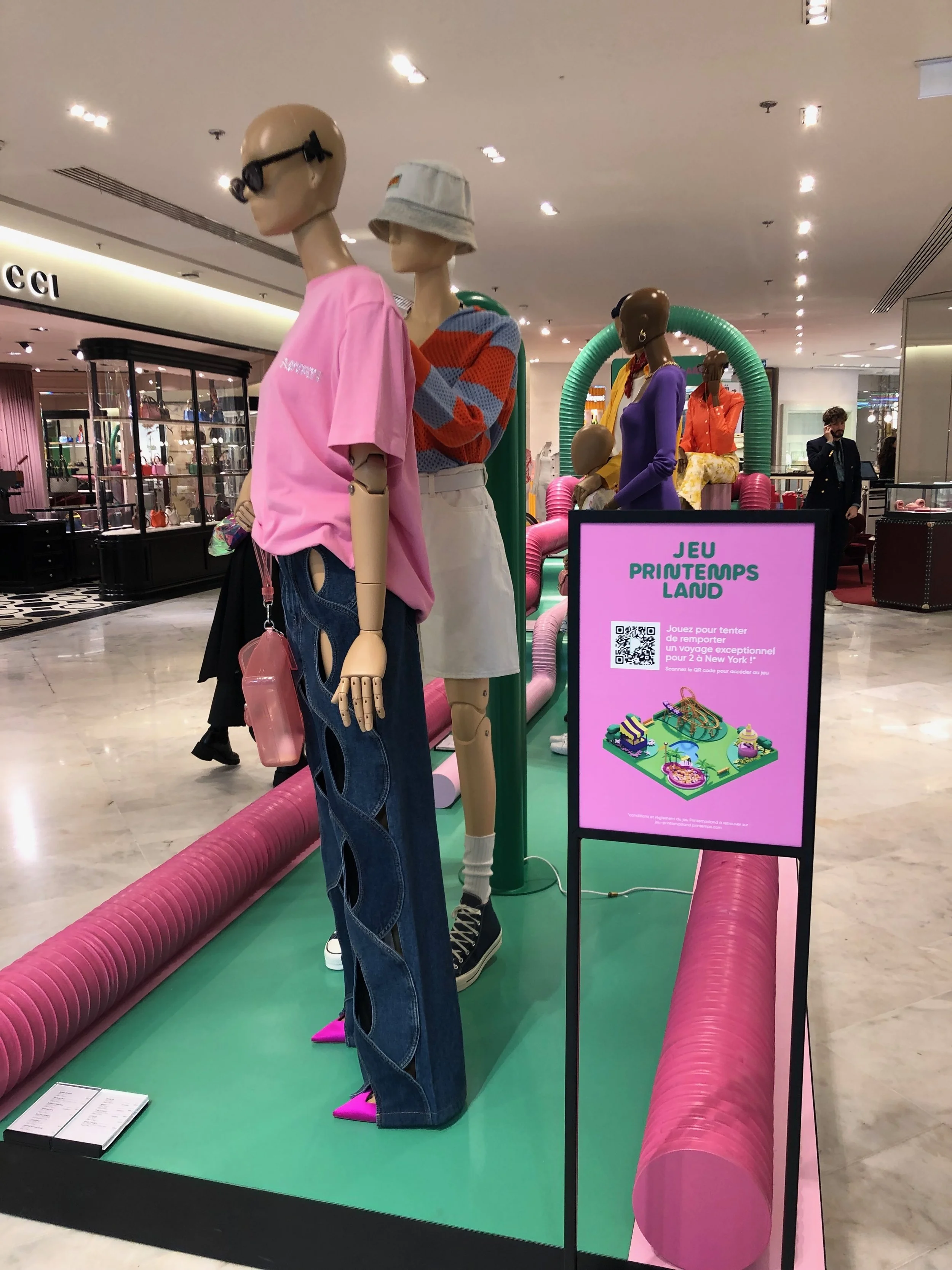 n-store digital touchpoint: a QR code panel next to mannequins, inviting shoppers to play the "Jeu Printemps Land" game for a chance to win a trip to New York.