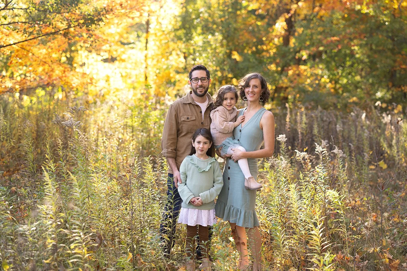 Family standing in a field with autumn foliage