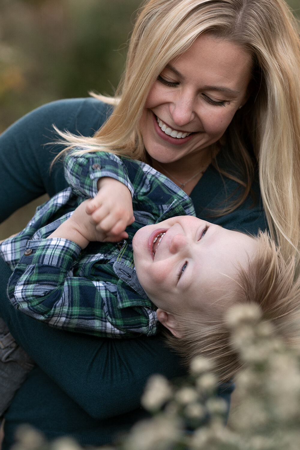 Smiling woman holding laughing child outdoors