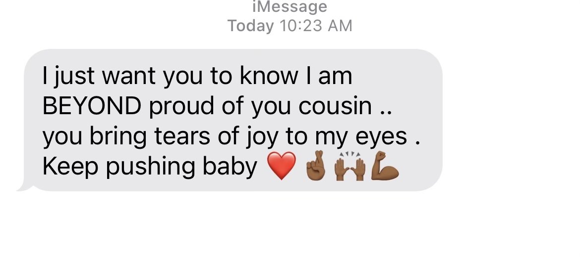 A text message on a phone screen with a heartfelt message of pride and encouragement, including emojis of a red heart, a flexed bicep, clapping hands, a raised fist, and a flexed arm.