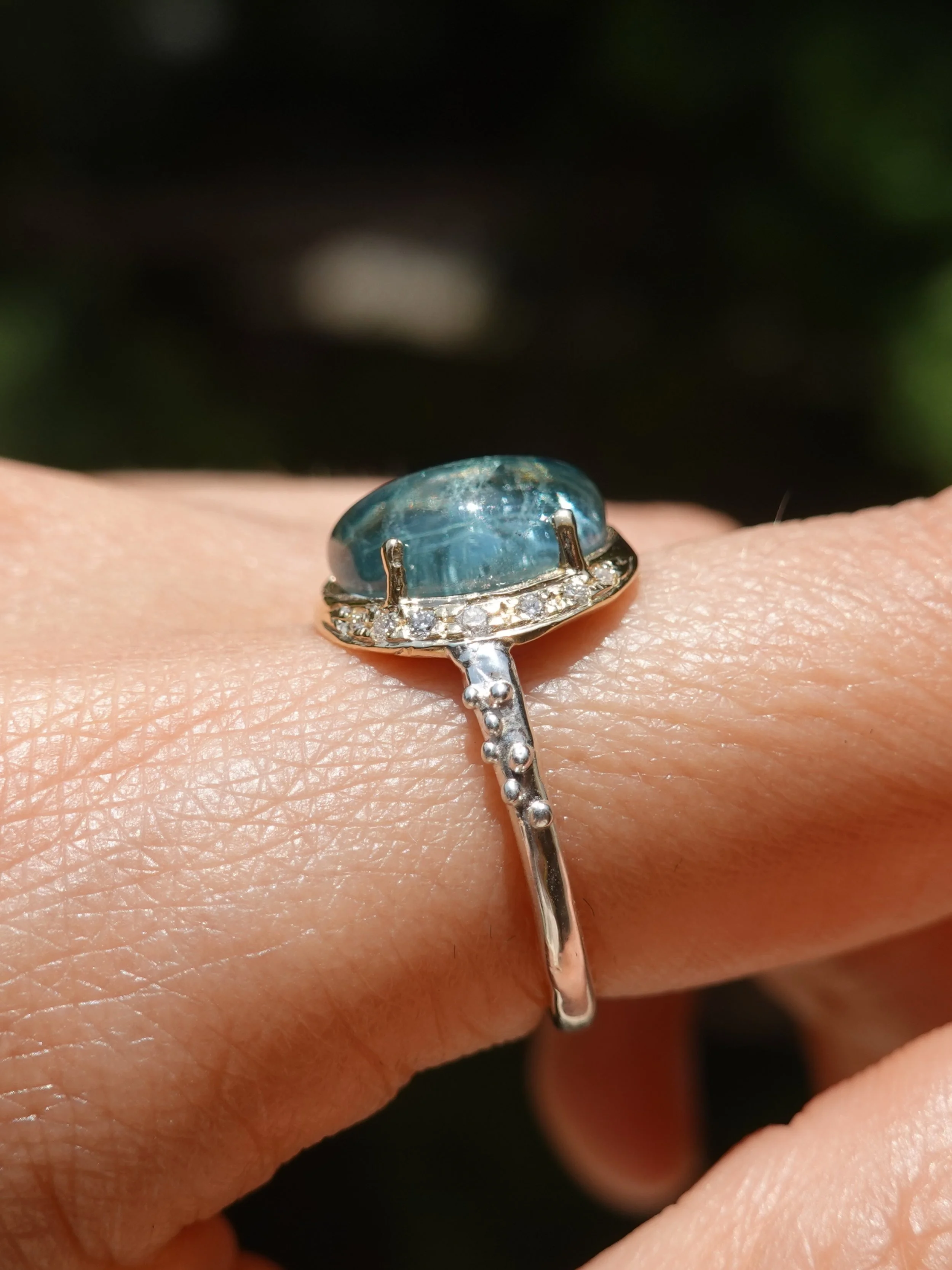 A Brazilian blue tourmaline shimmers like tropical tide pools in a calm sea. I am *in love* with this cut -  a unique half moon shape to enhance its soothing blue hue 💙🌝

Glowing in a 14k yellow gold setting with a sterling silver bubbly band, this