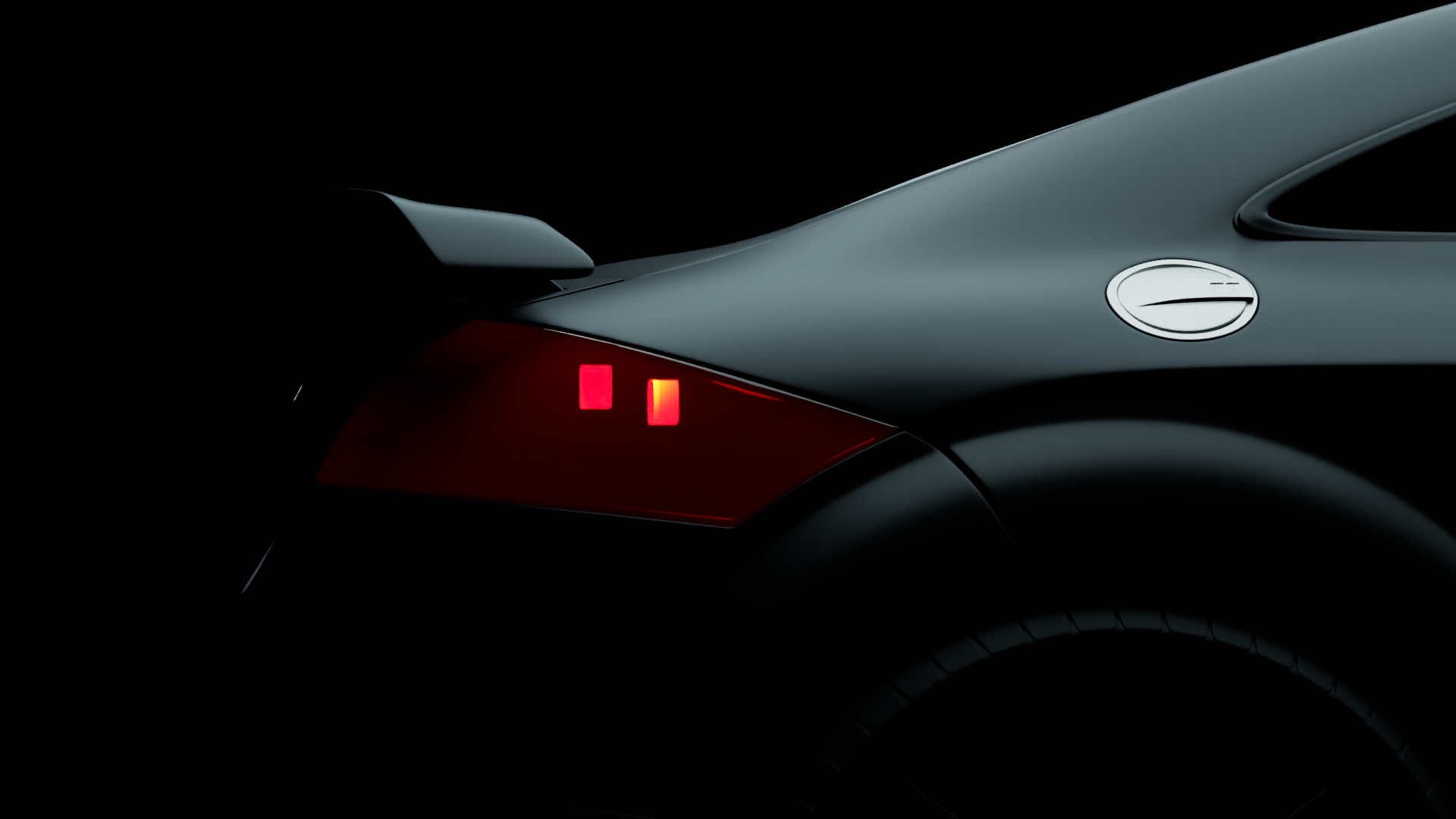 Close-up of the rear of a sleek, dark gray sports car showing detail of the taillight, rear wing, and part of the rear wheel.