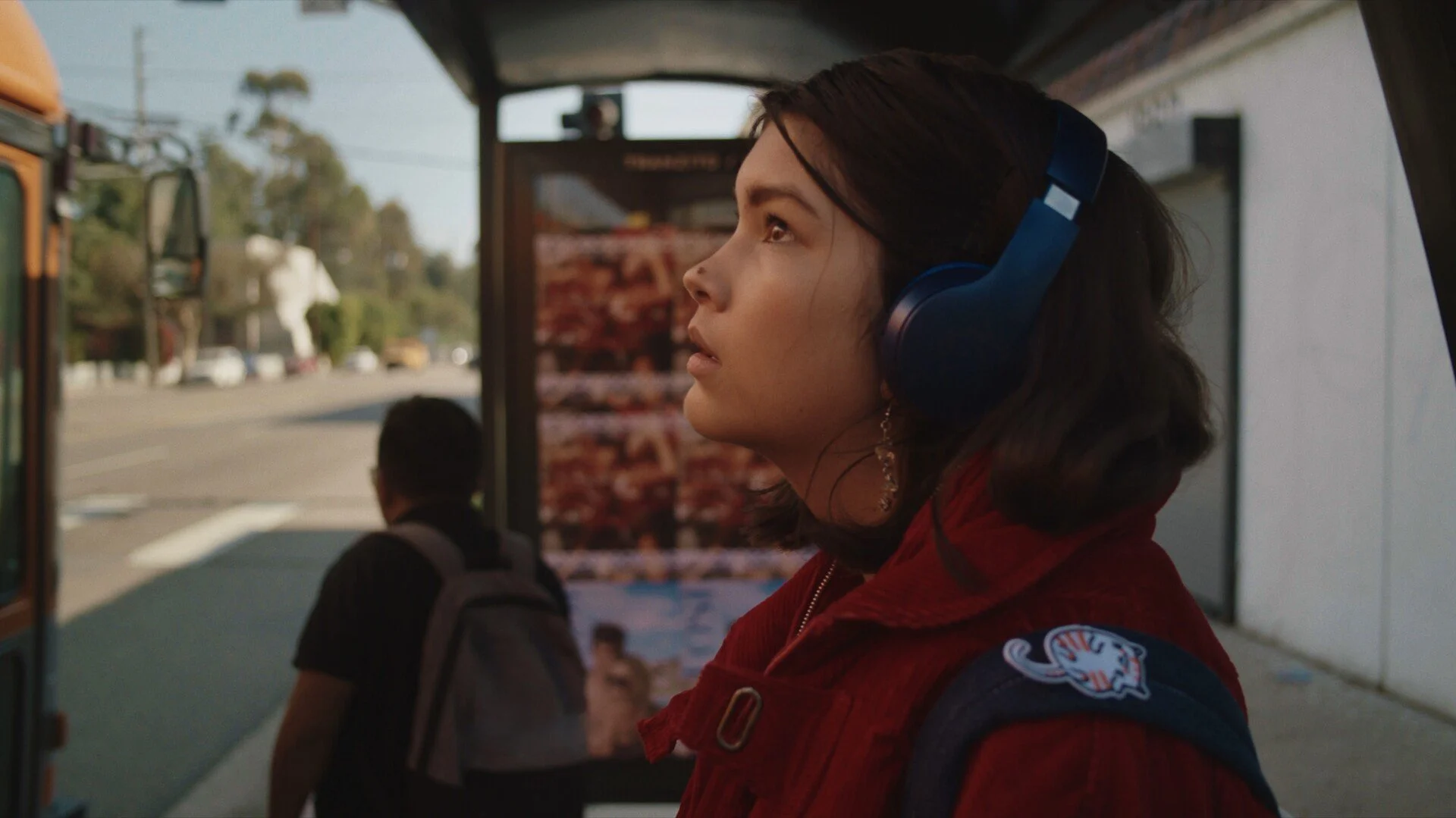 a girl looking up at the sky at a bus stop