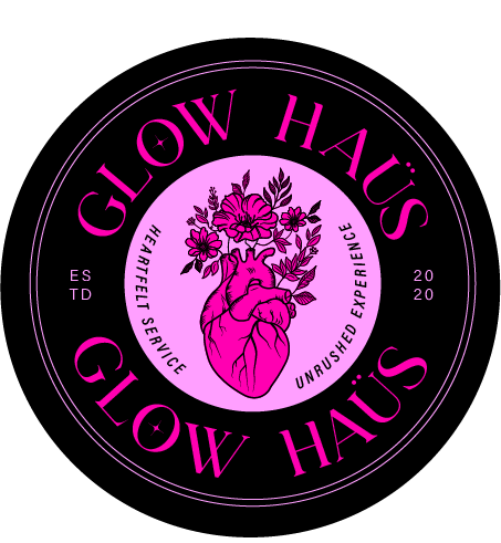 A circular logo with the text Glow Haus repeated twice, featuring a detailed illustration of a human heart with flowers and leaves growing from it, in pink and purple hues on a black background.