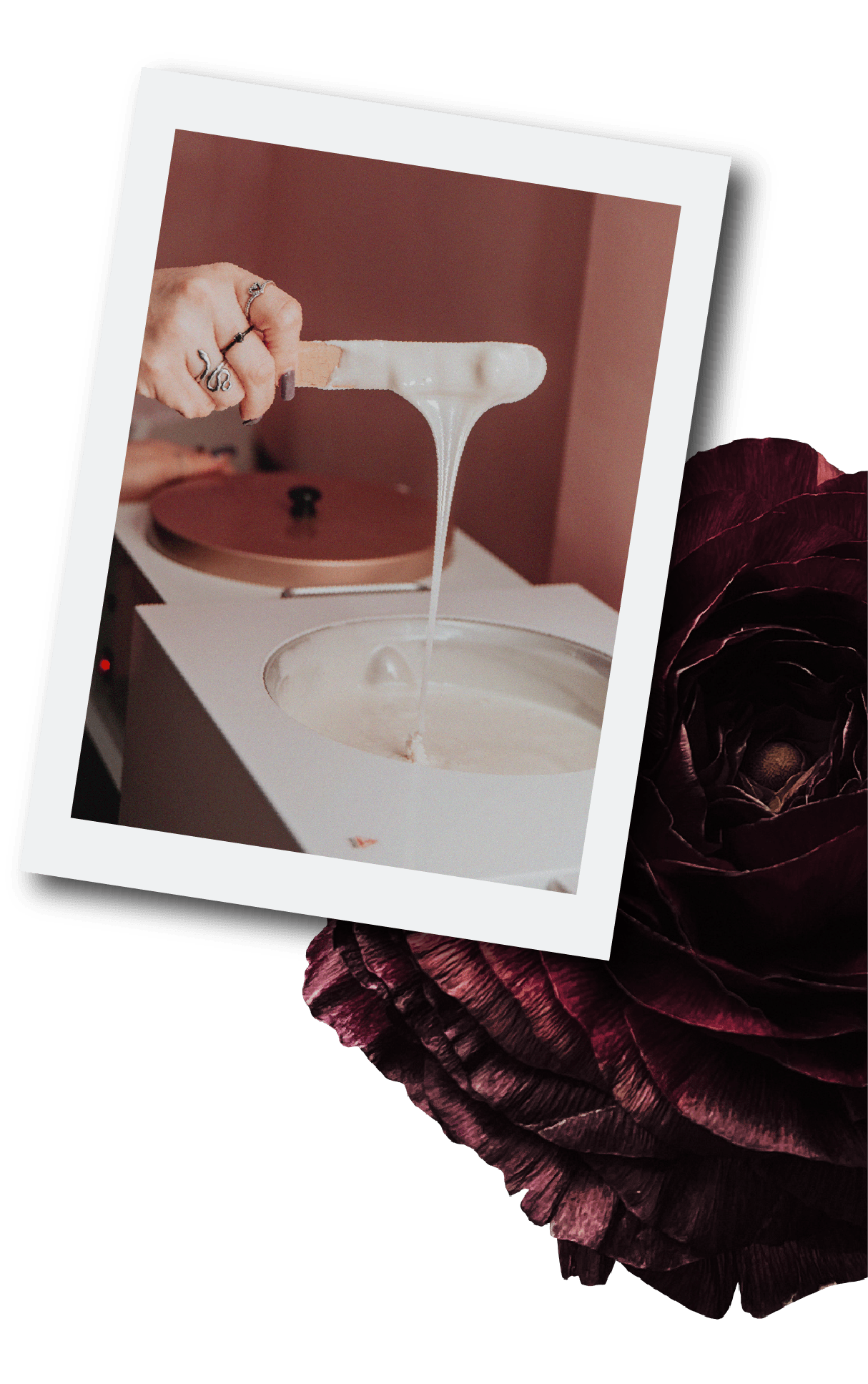 A hand stirring white paint from a container with a paint stir stick, with a turntable and a brown background in the background.