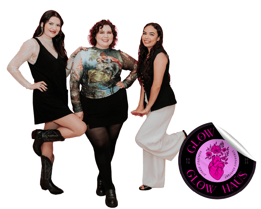 Three women standing together, smiling, with one woman on the left lifting her right leg, wearing black boots, and another woman on the right wearing white pants. A logo in the bottom right corner reads 'GLOW HAUS' with a pink heart-shaped leaf, a heart with a plant growing from it
