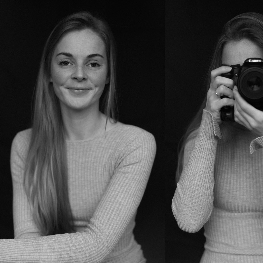 A woman with long hair smiling at the camera, while another woman is taking her photo with a camera, both in black and white.