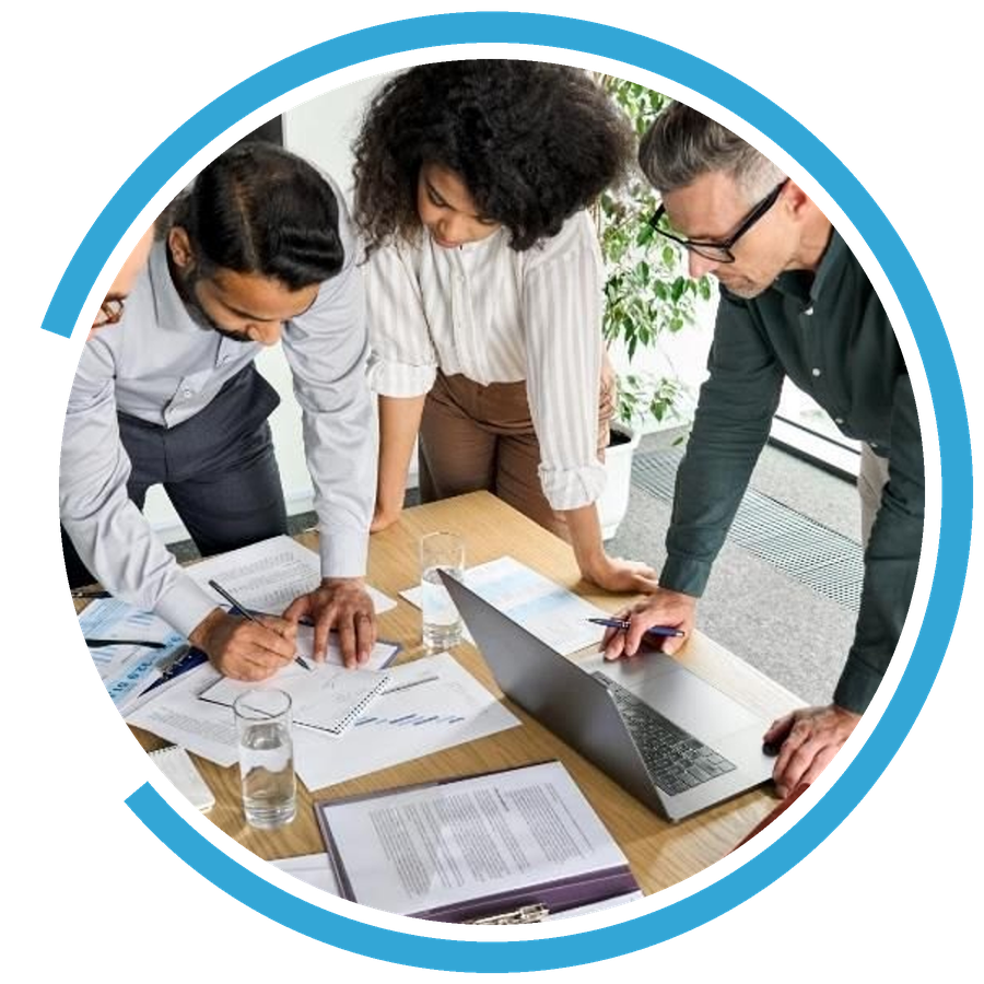Colleagues leaning over a table of printed reports and a laptop, working through a plan together