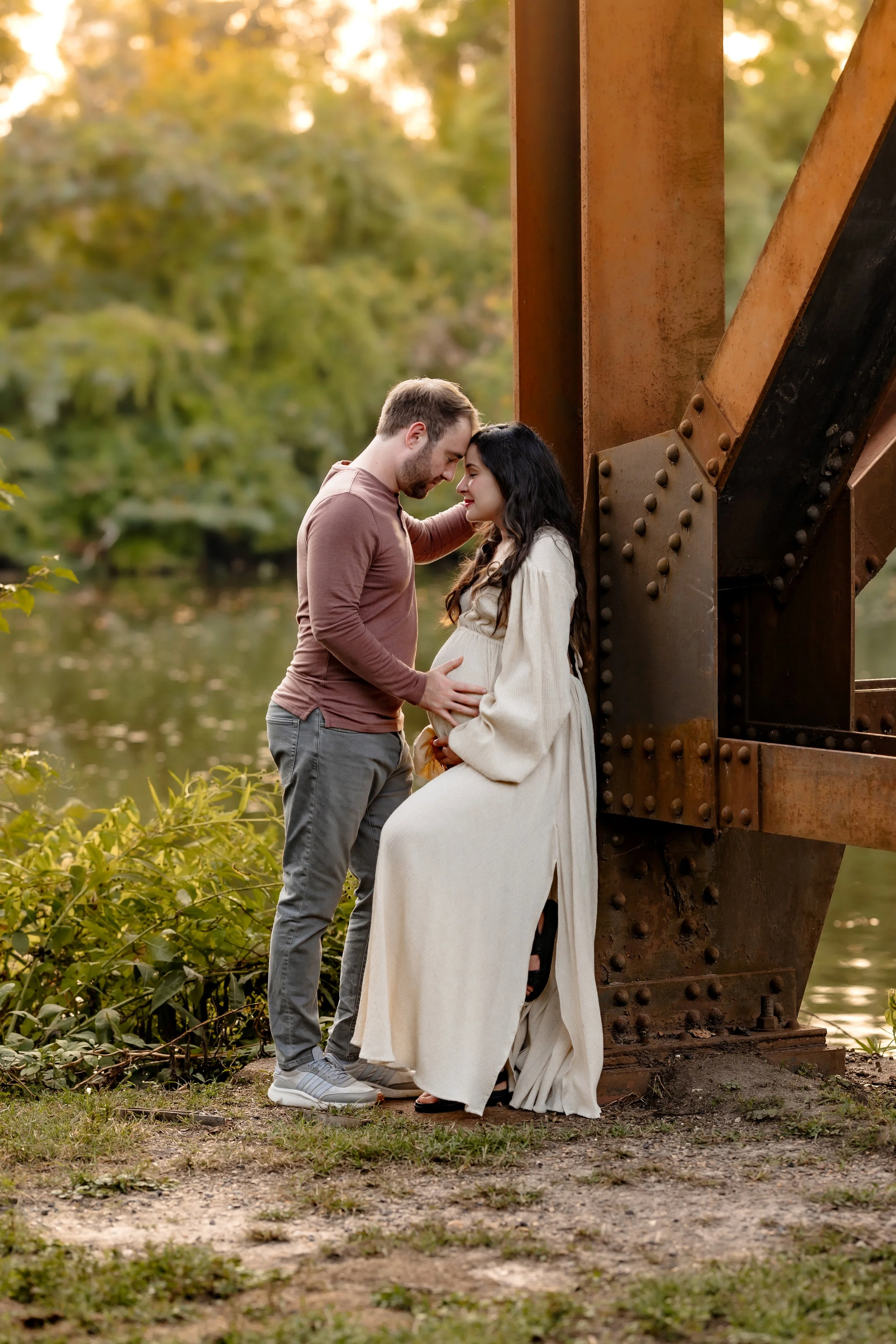 expectant mother holding her belly with father during a golden hour session in Richmond, VA
