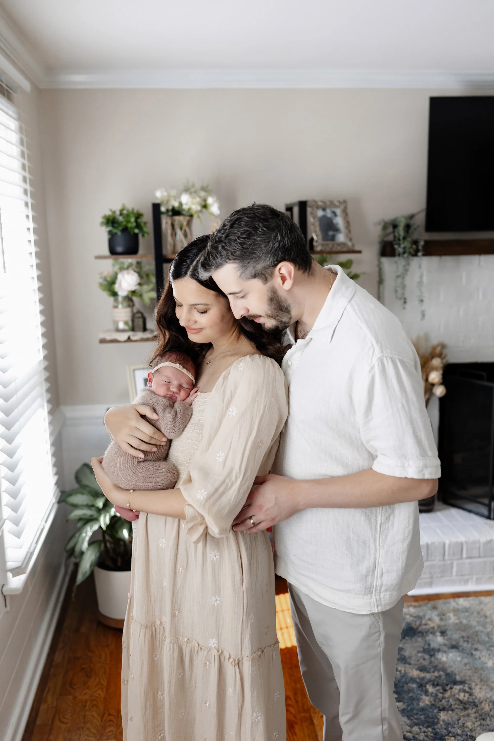 mother and father holding their newborn baby boy in their home with soft sunlight and peaceful