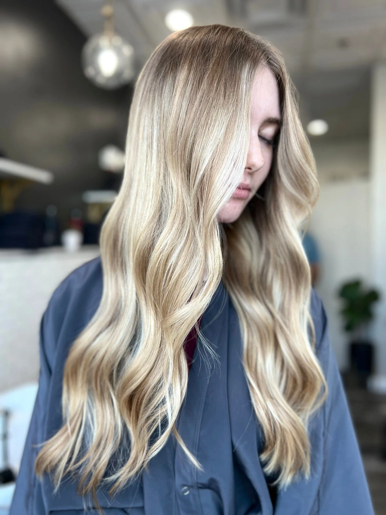 Woman with long, wavy blonde hair in a salon setting.
