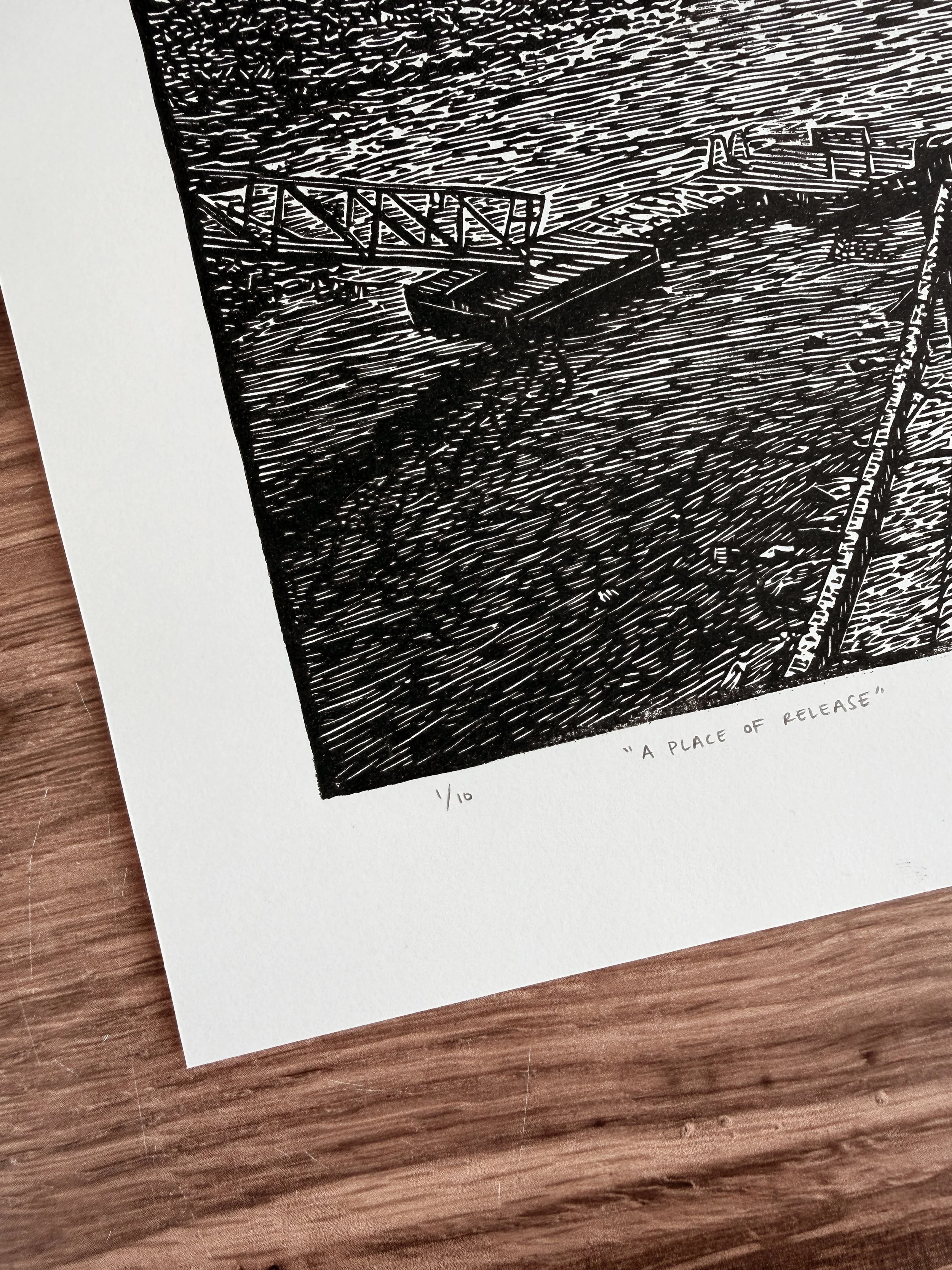 Close-up of linocut print showing dock and water with carved line texture, titled A Place of Release