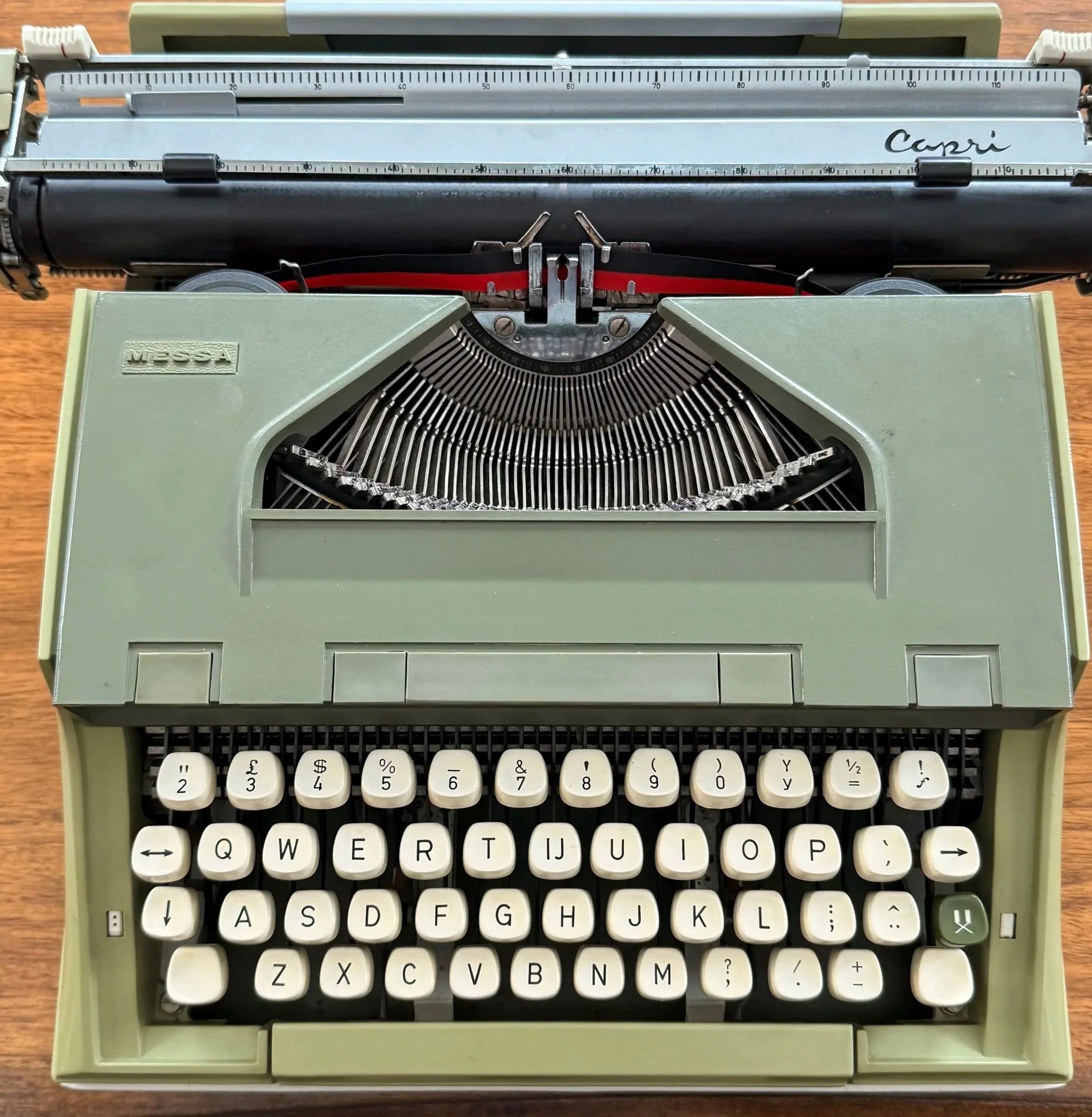Close-up of vintage typewriter keys in soft green casing, symbolizing slow writing and intentional creative process.