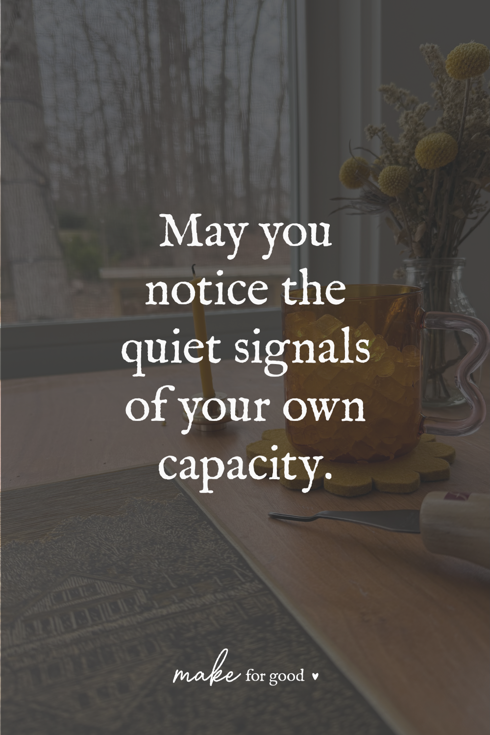 An amber glass mug, candle, dried flowers, and carving tools on a wooden table near a window, with text reading “May you notice the quiet signals of your own capacity.”