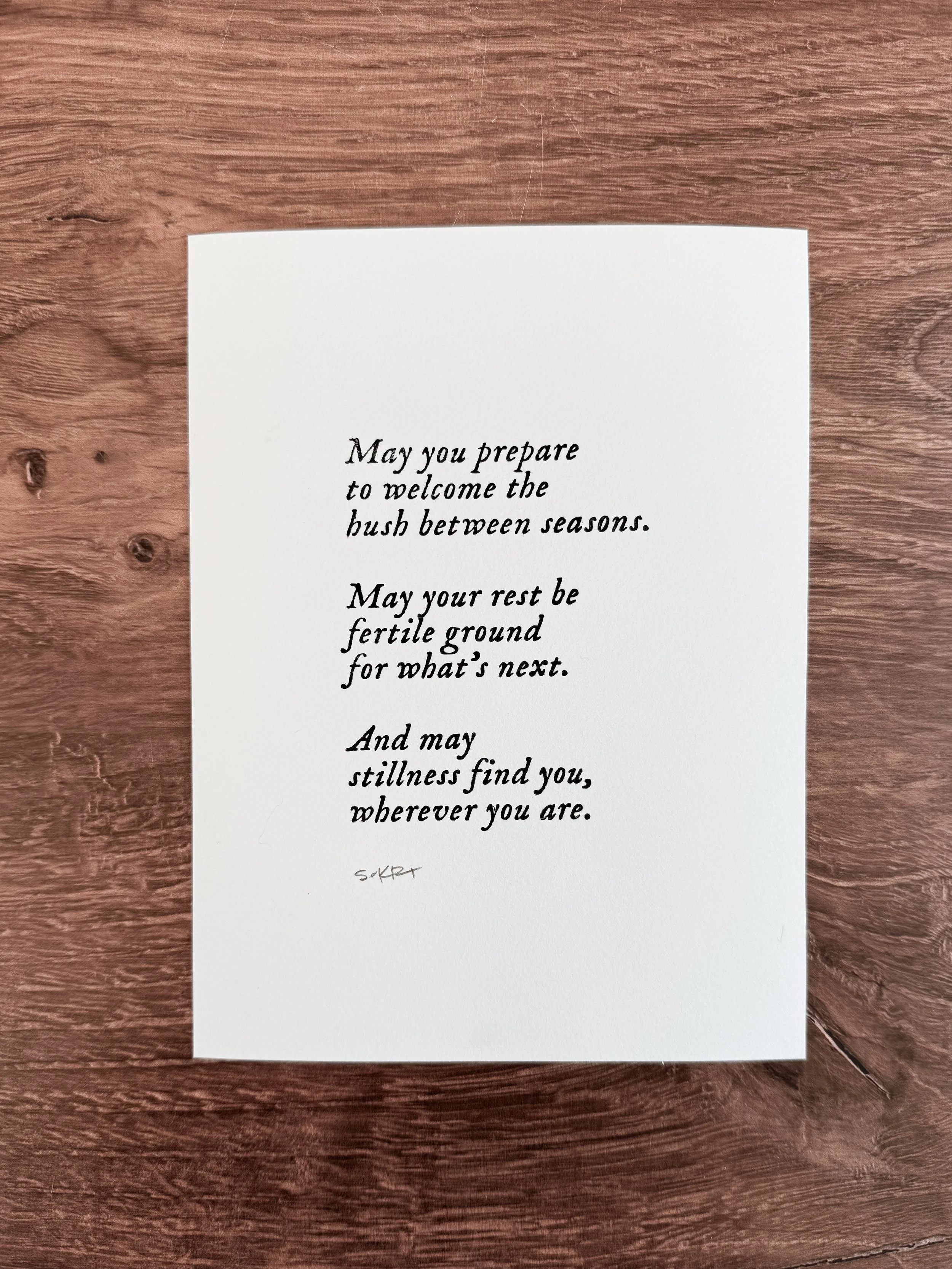 Hand-printed benediction art print on white paper with centered text about the hush between seasons
