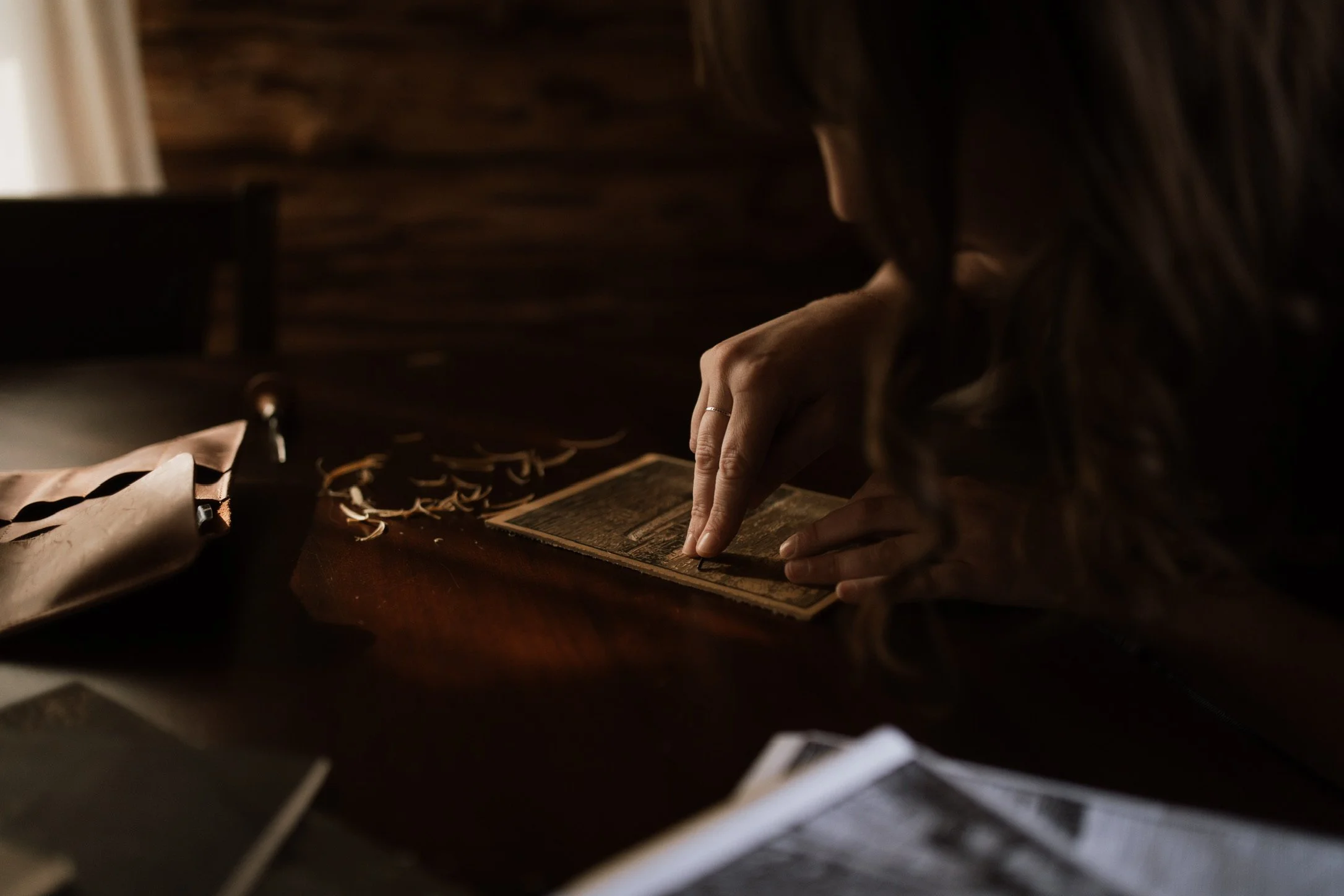 Close-up of hands carving a linocut print block with fine detail tools