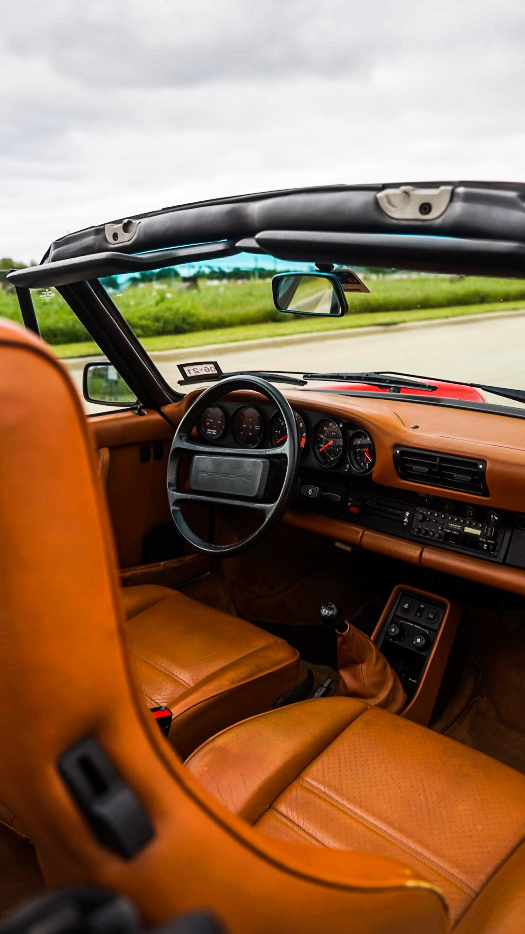 Interior of a vintage convertible car with tan leather seats and classic dashboard.