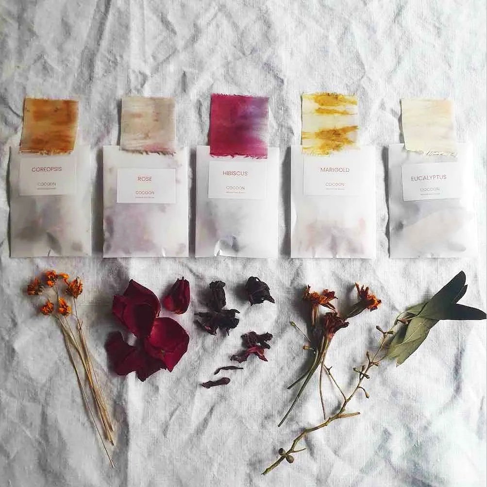 Five sachets of natural dyes in a row with fabric colour samples above.