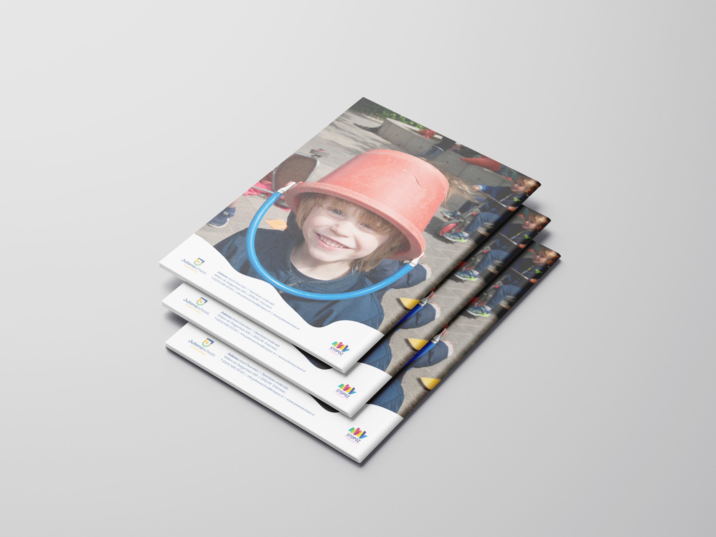 Een stapel brochures met een afbeelding van een lachend kind met een rode emmer op het hoofd.